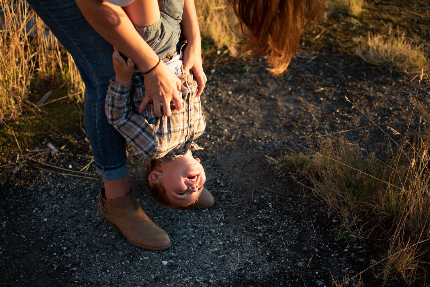 Parents playing upside-down with toddler at sunset, Chesapeake VA candid family photographer.
