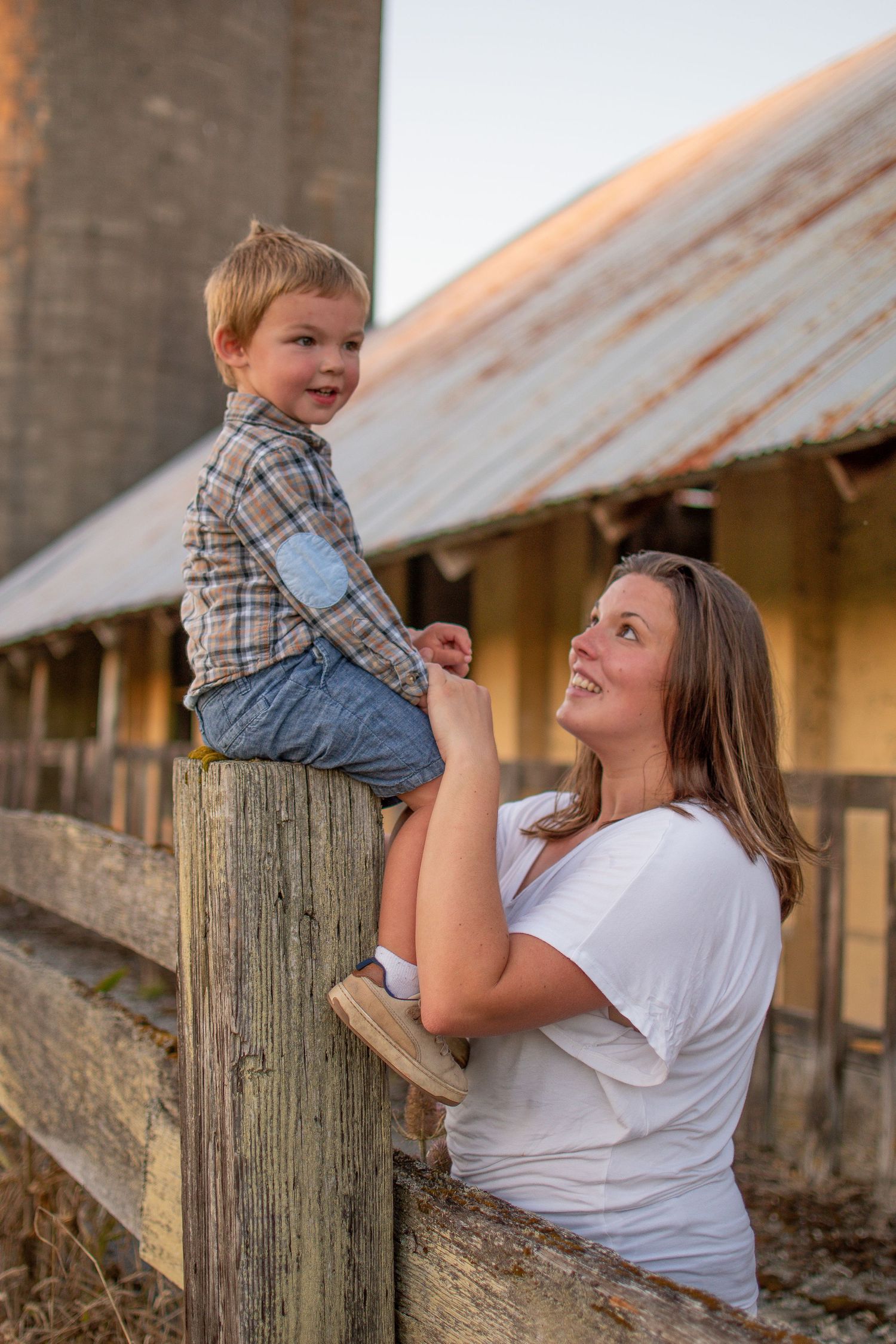 Mother lifting son near rustic wooden fence, Chesapeake VA family photographer.