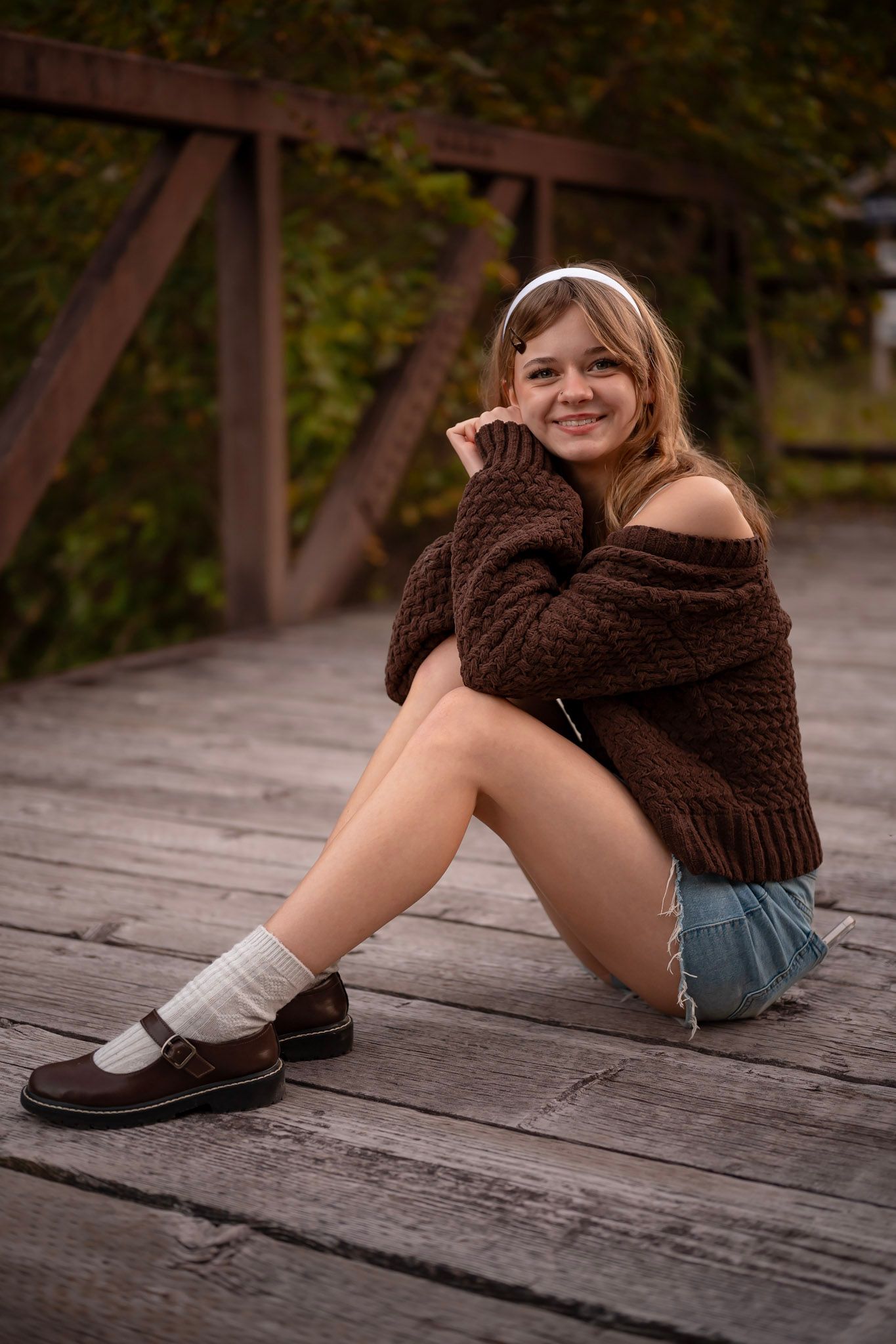 Teen girl sitting on rustic bridge at golden hour, Chesapeake VA portrait photographer.
