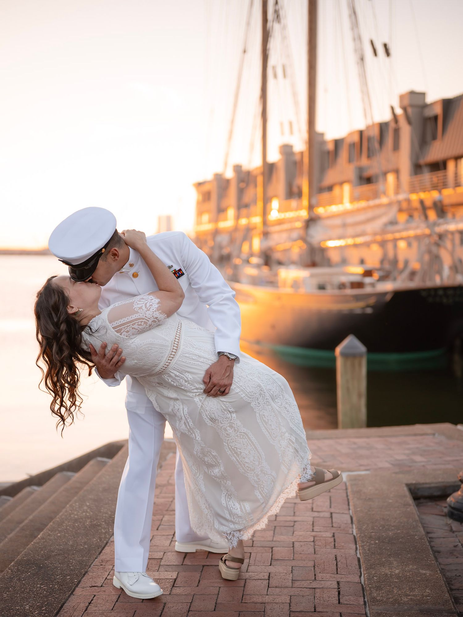 Navy sailor in uniform dipping his partner for a kiss by the pier -romantic military couples phone by Photography by Kylee Mason, Chesapeake