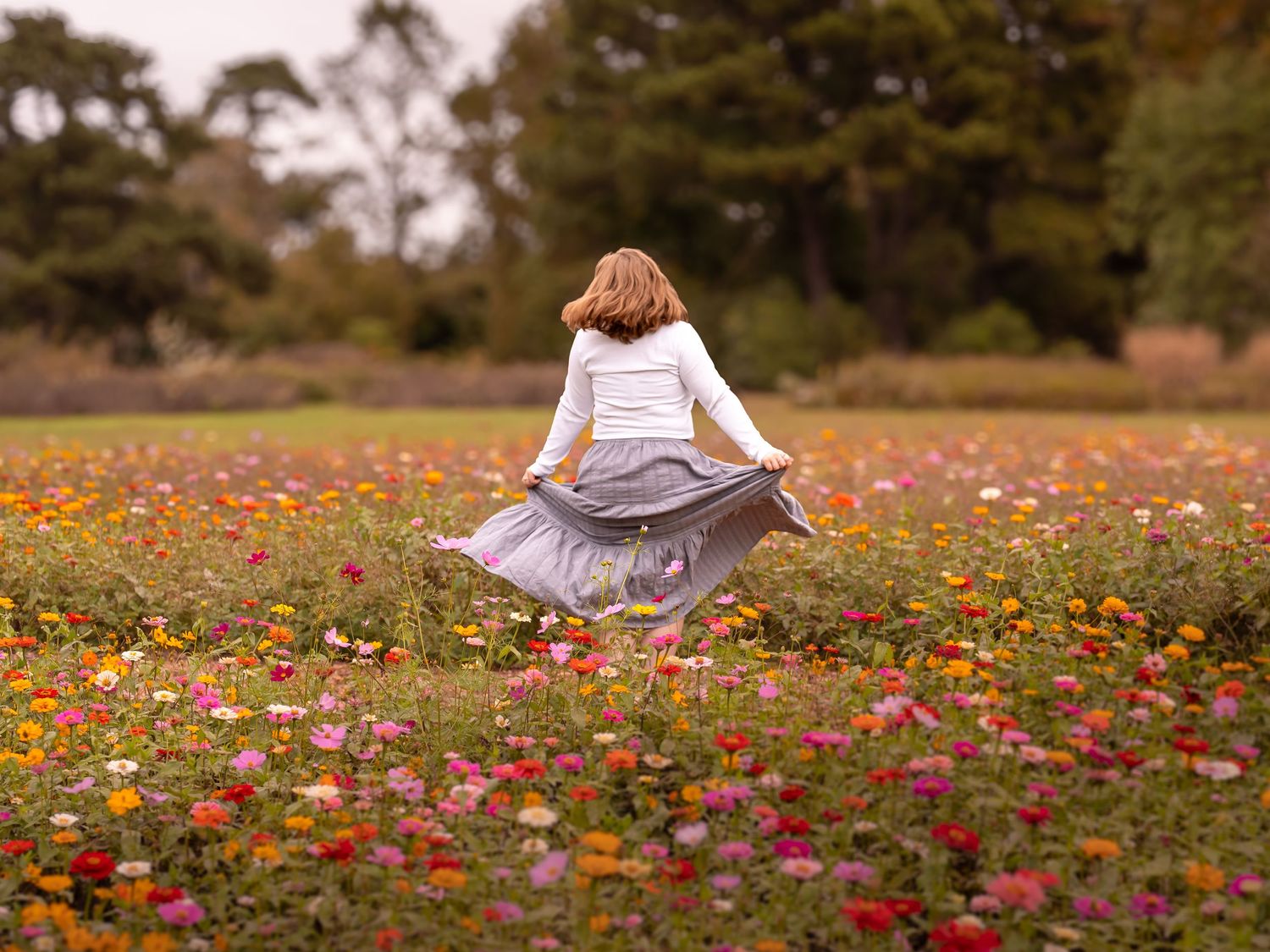 Beautiful woman twirling in the field of wild flowers in Norfolk, VA at the Botanical Gardens.