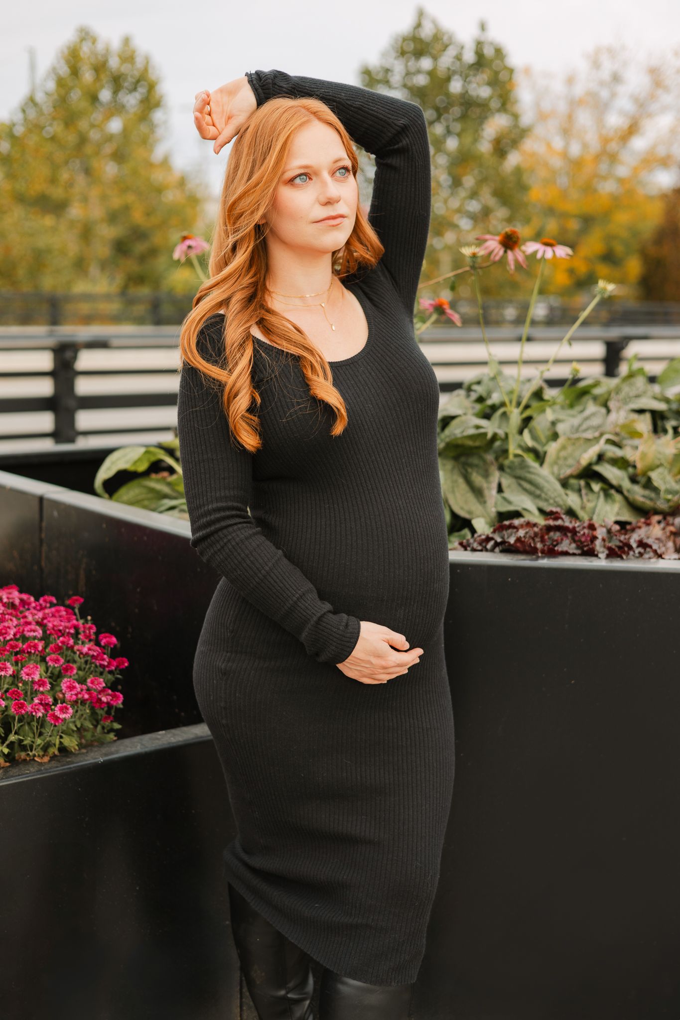 Fall Maternity Session woman wearing black with left arm over head and right arm under baby bump