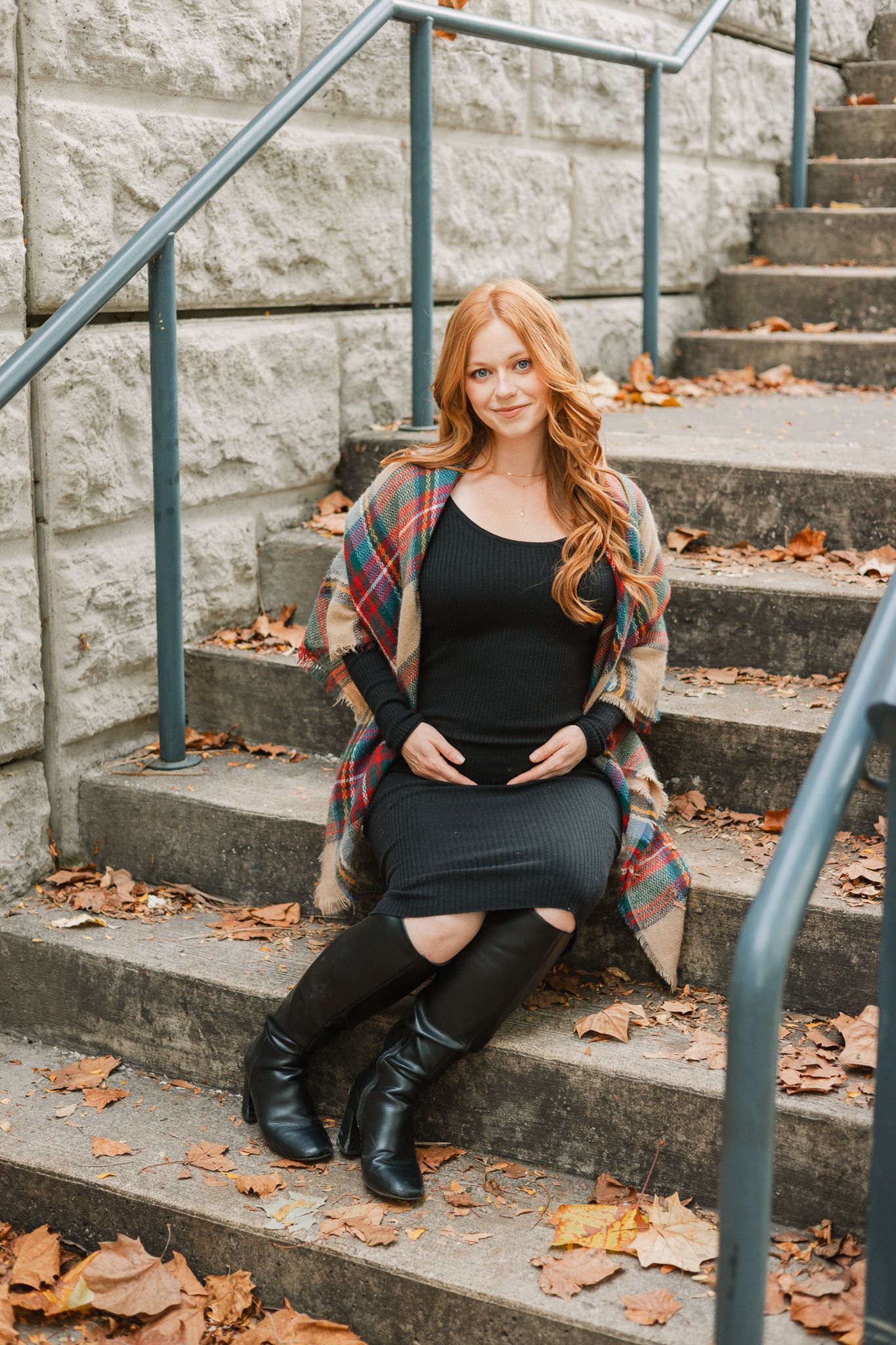 fall maternity session mom to be wearing black dress sitting on steps holding her baby bump
