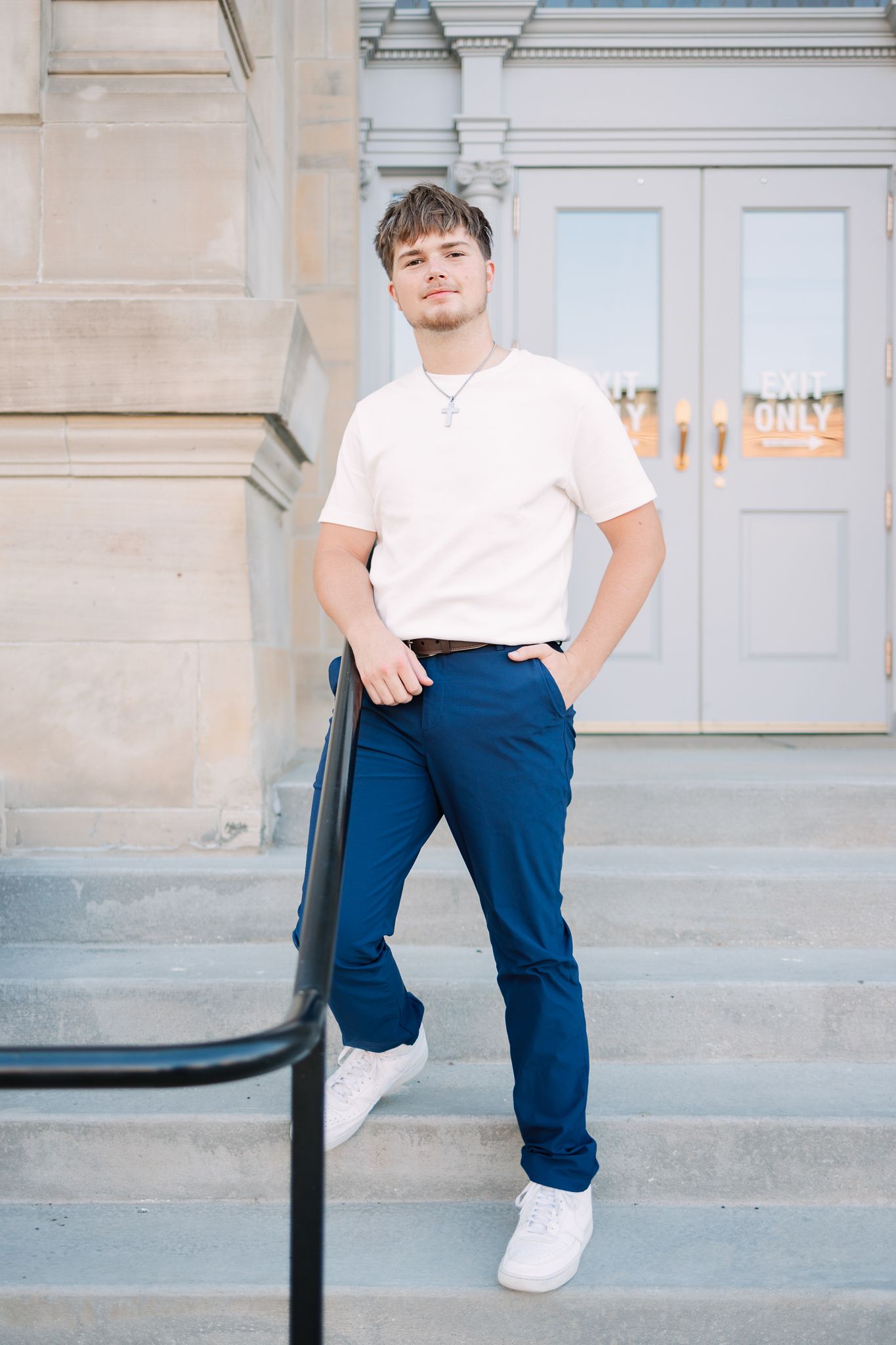 senior leaning against railing leading up to the entrance to a courthouse