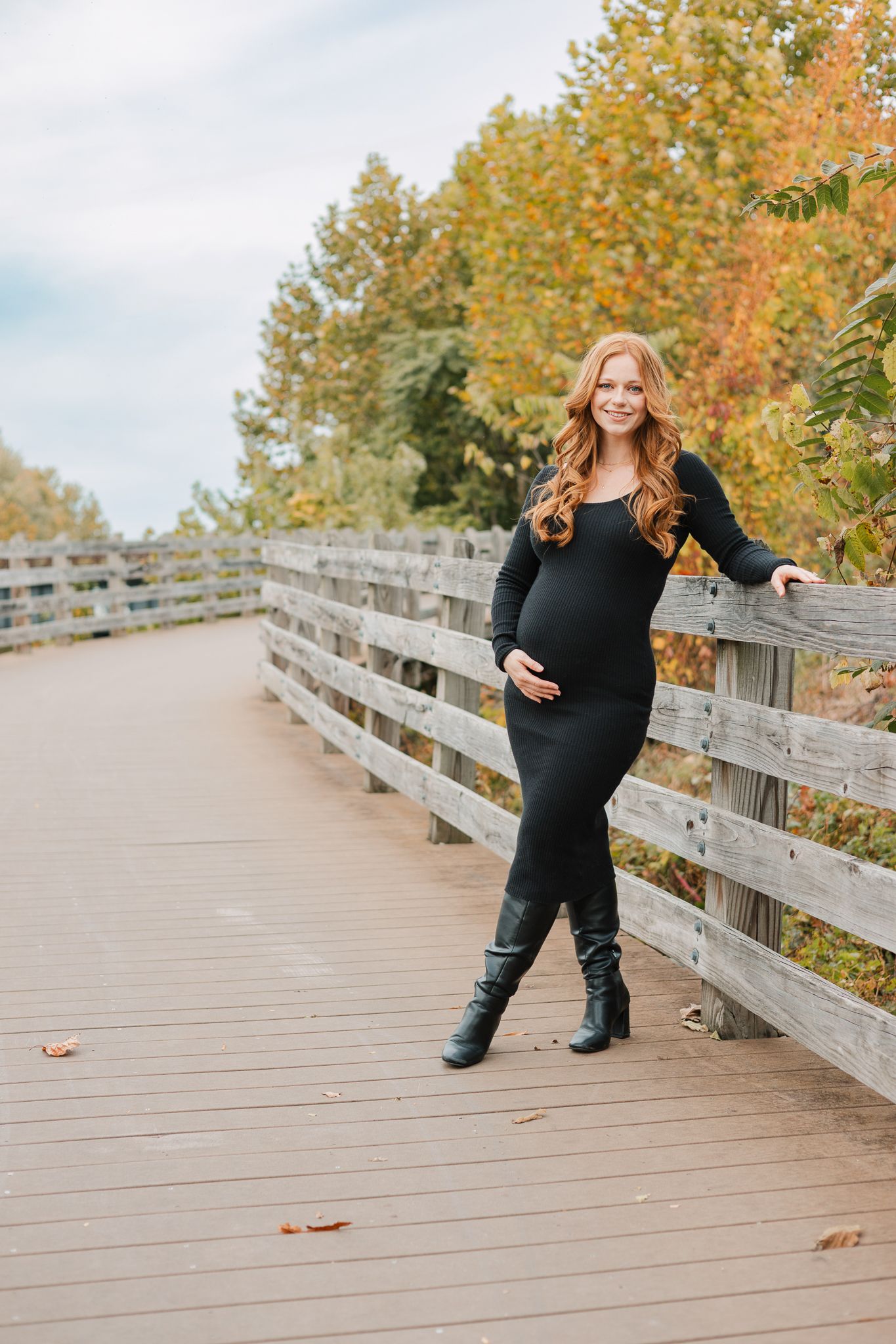 fall maternity on a bridge next to a wood fence