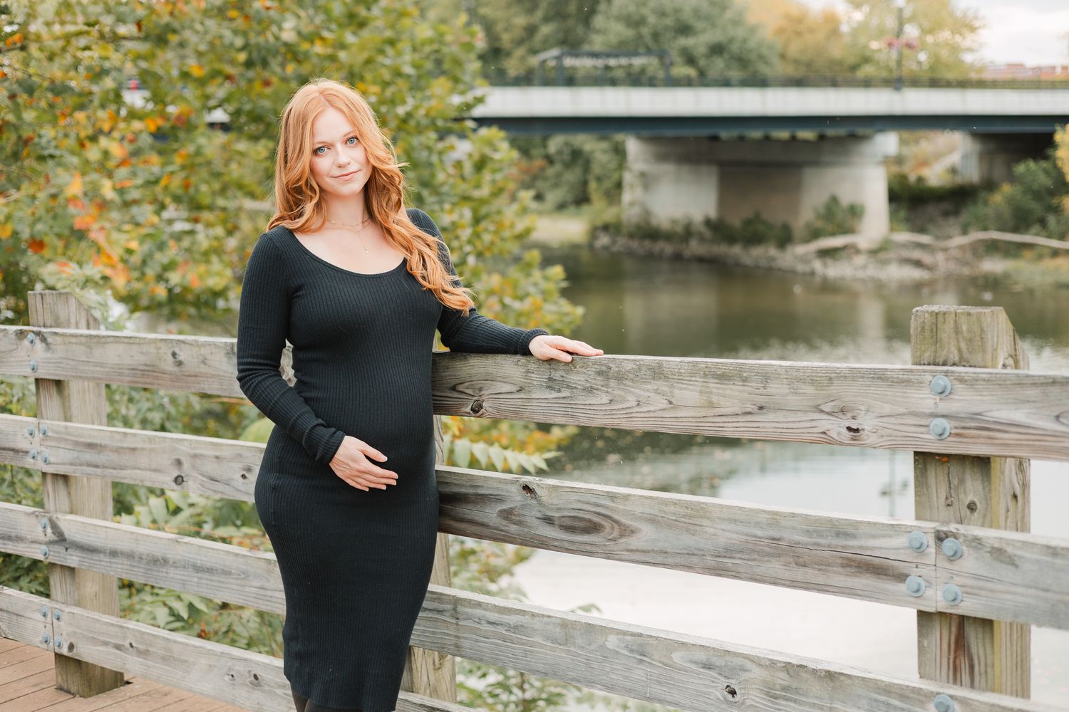 fall maternity next to fence in front of bridge