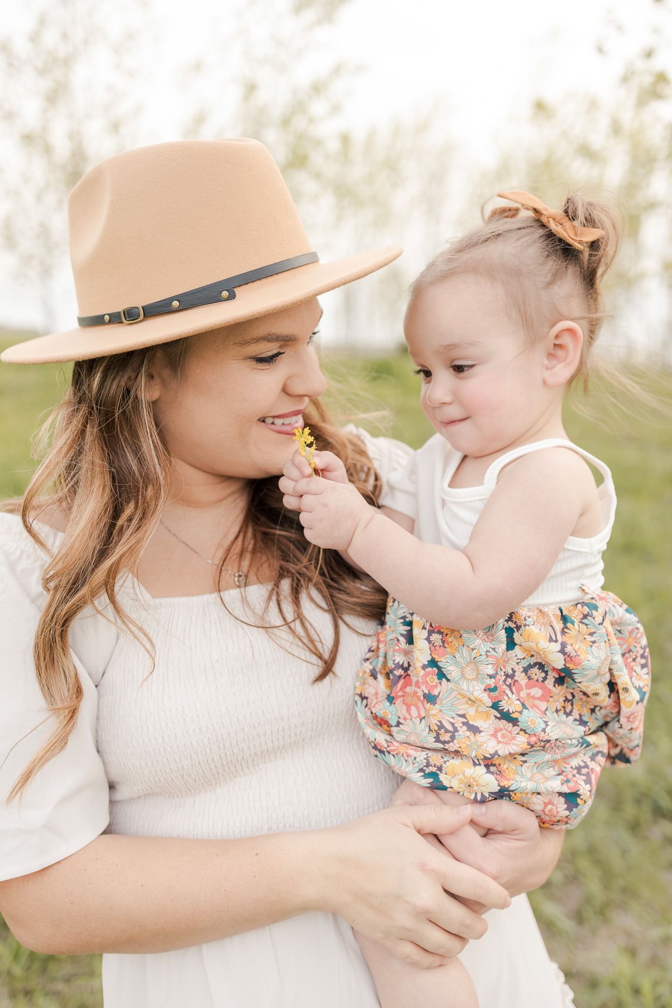 mom and toddler daughter being held in a field