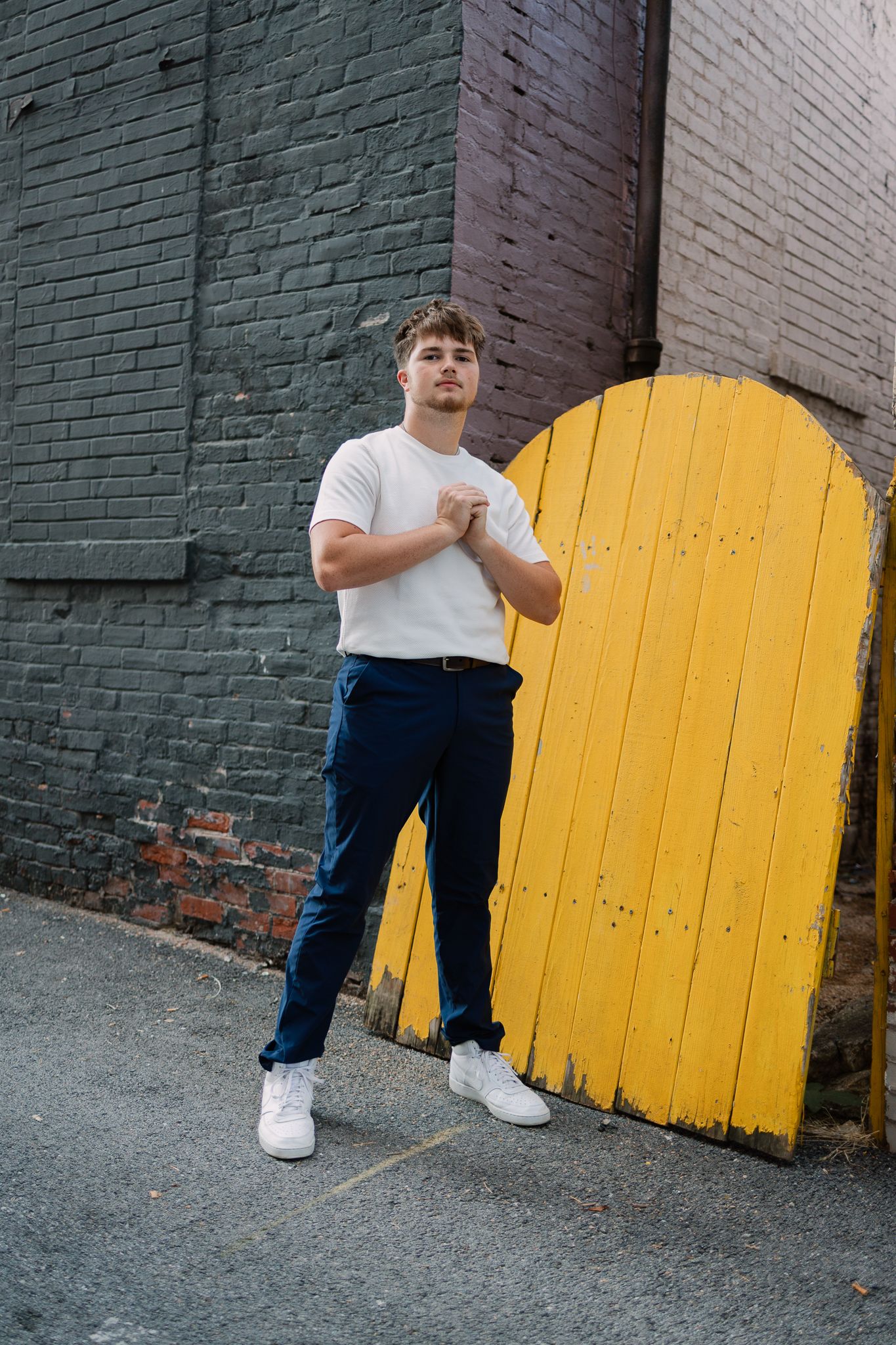 senior standing in front of a yellow gate