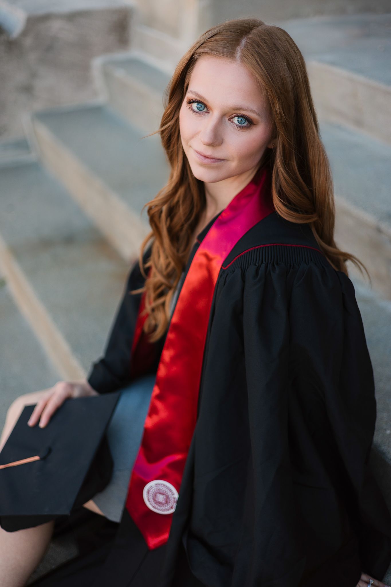 college graduate sitting on steps while holding her cap in Noblesville, IN