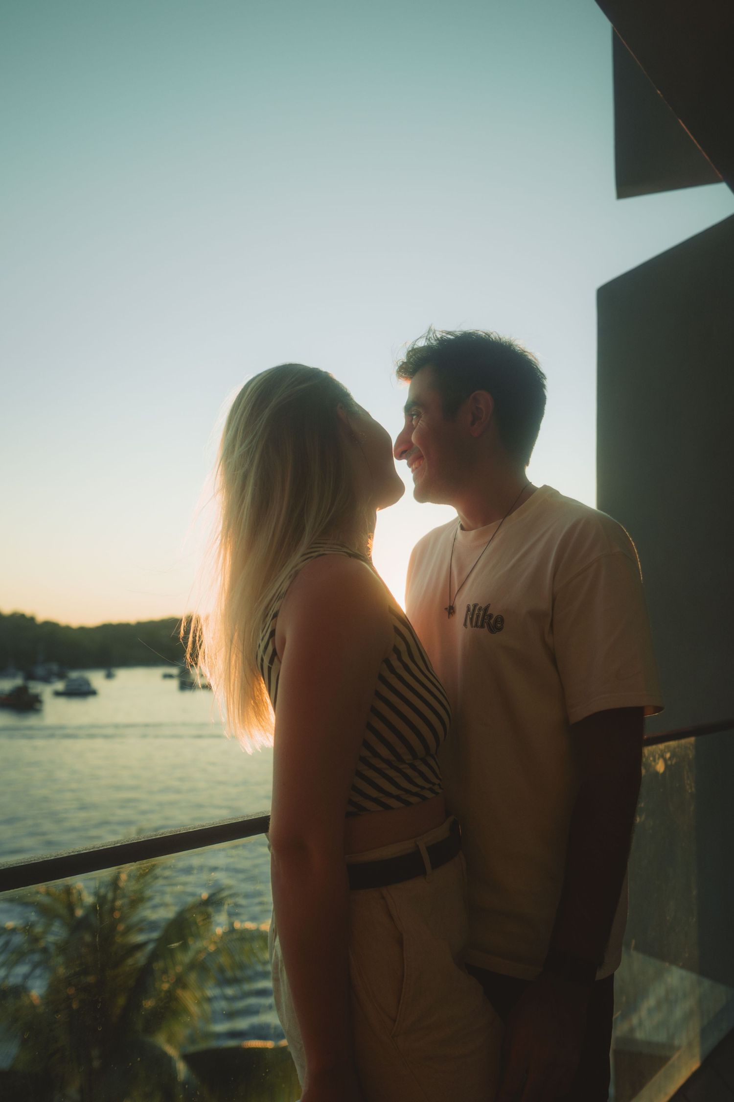 Silhouettes of a couple sharing an intimate moment on a boat deck at sunset.