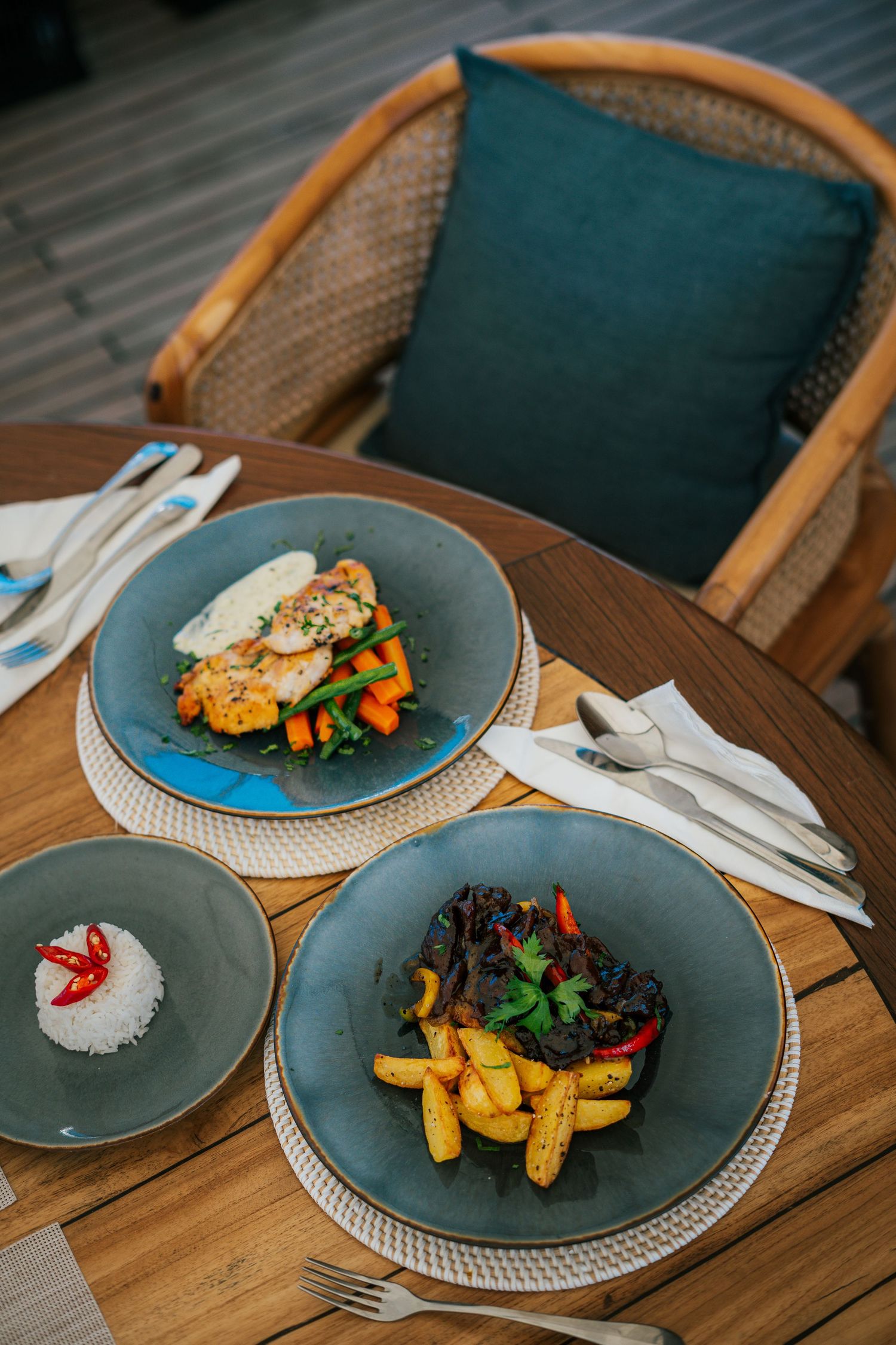 Beautifully plated dishes with colorful vegetables served on gray plates on a wooden table.