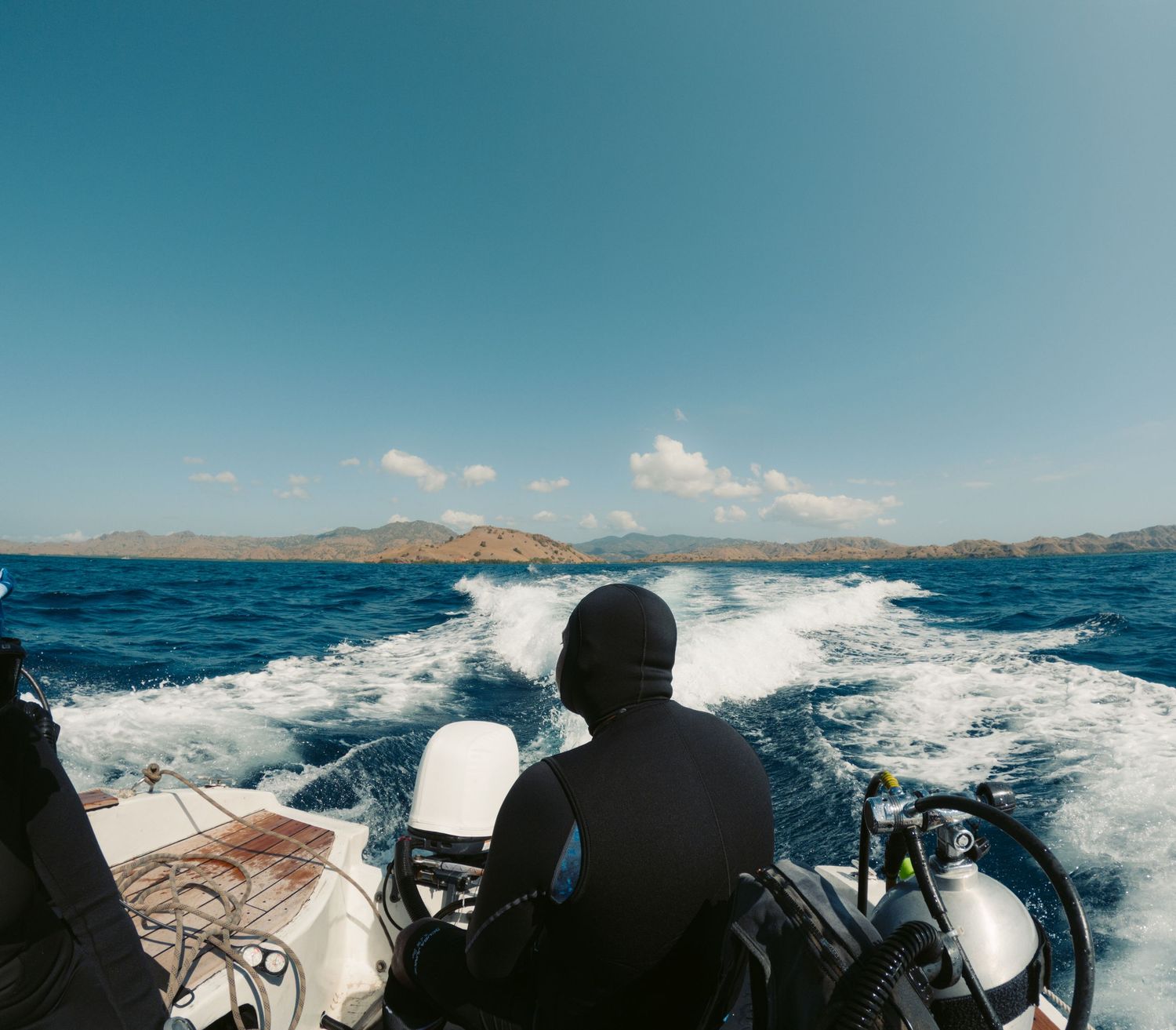 View from a moving boat showing wake patterns in blue ocean water.
