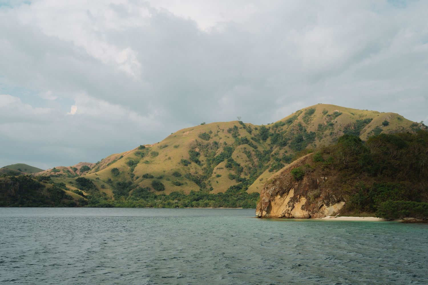 Panoramic view of rugged coastal mountains and bays under cloudy skies.