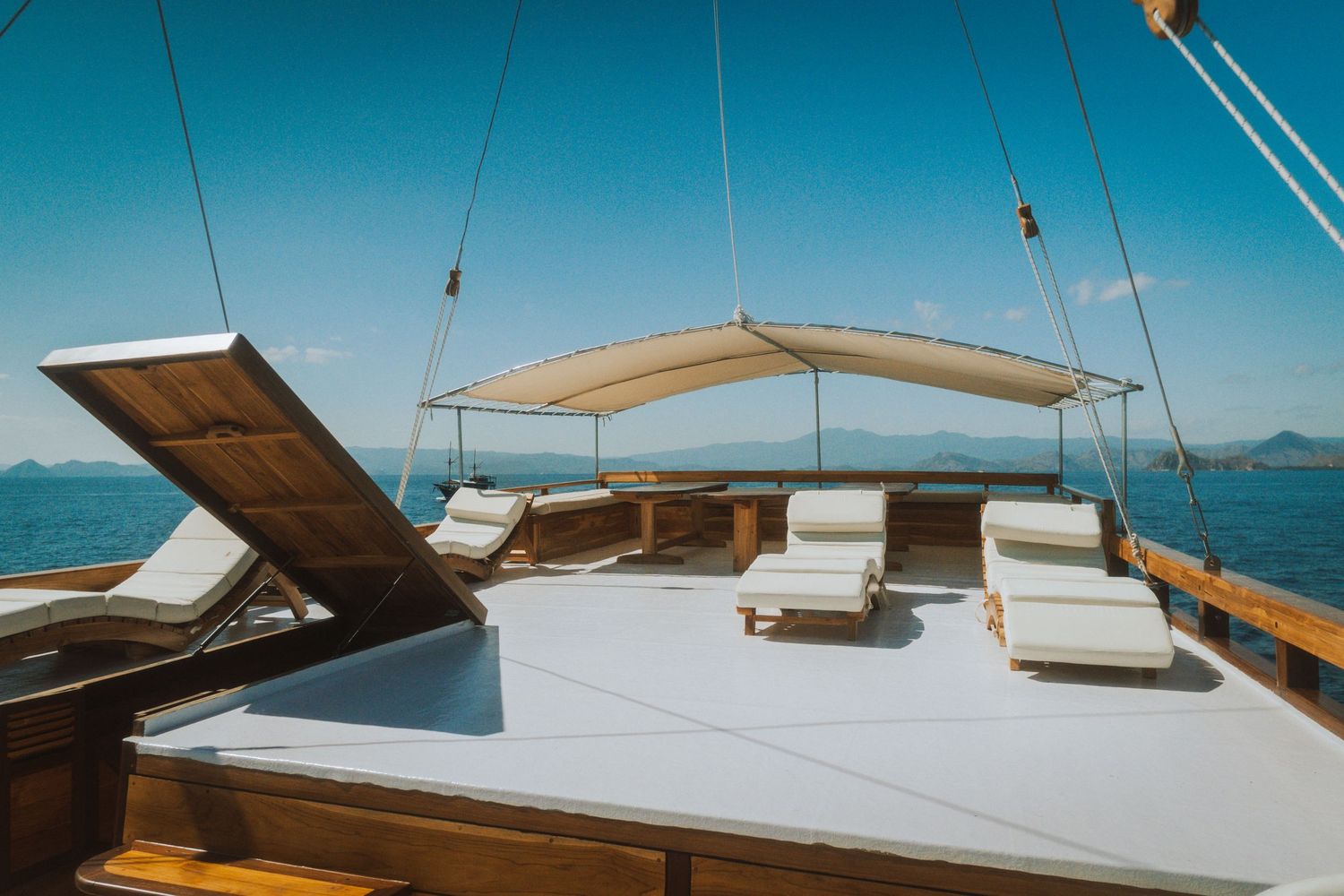 White cushioned lounge areas on the deck of a luxury sailing yacht with ocean views.