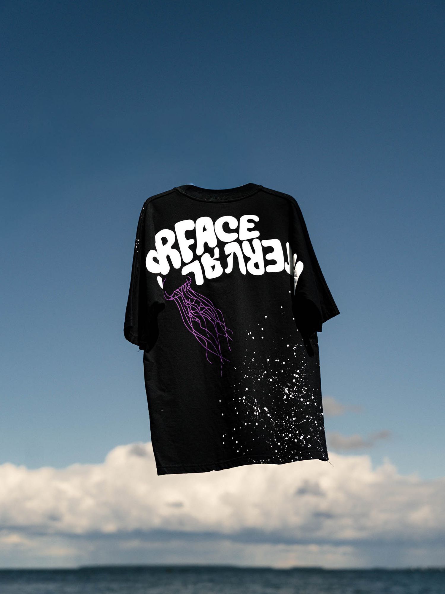 Black t-shirt with 'Peace Between' text floating against blue sky and clouds.