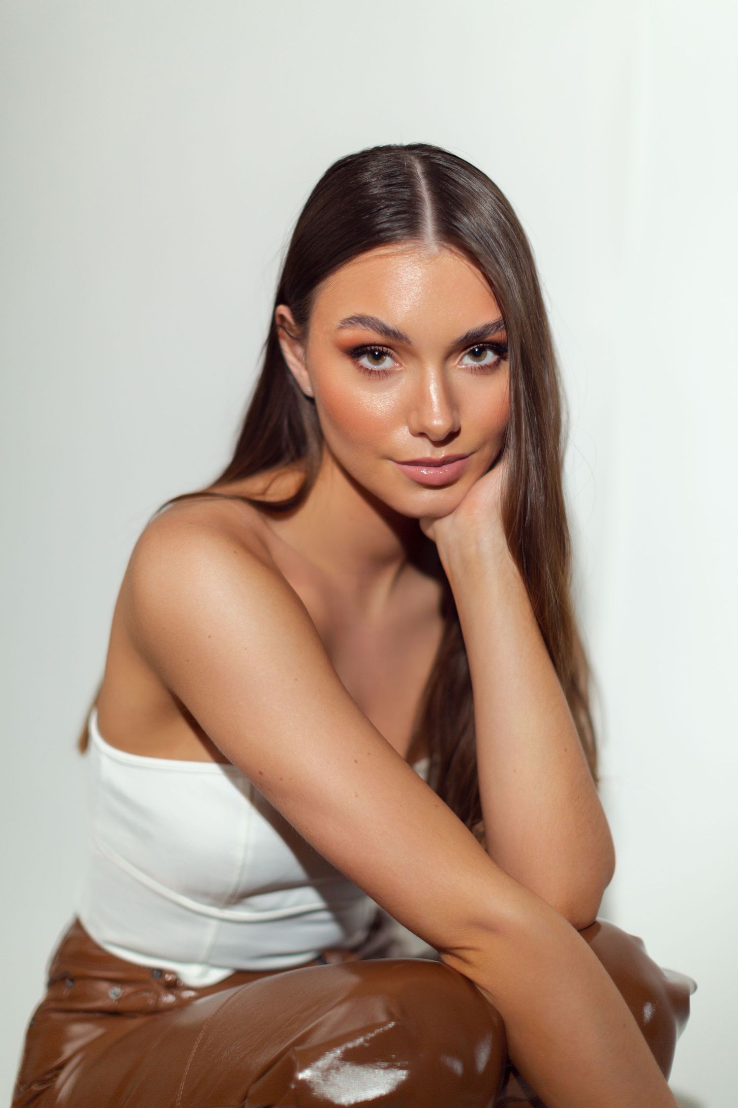 Studio portrait series in warm tones featuring a white sleeveless top against neutral background.