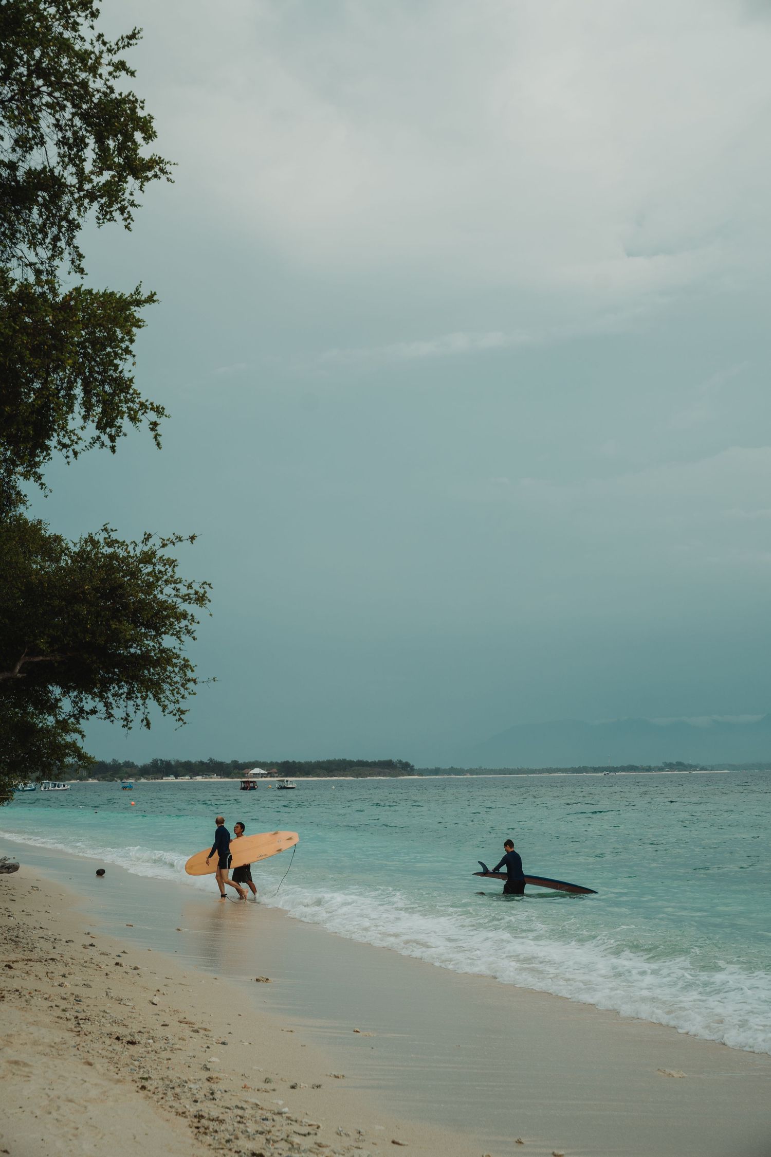 People enjoy a cloudy day at a tropical beach with turquoise waters.