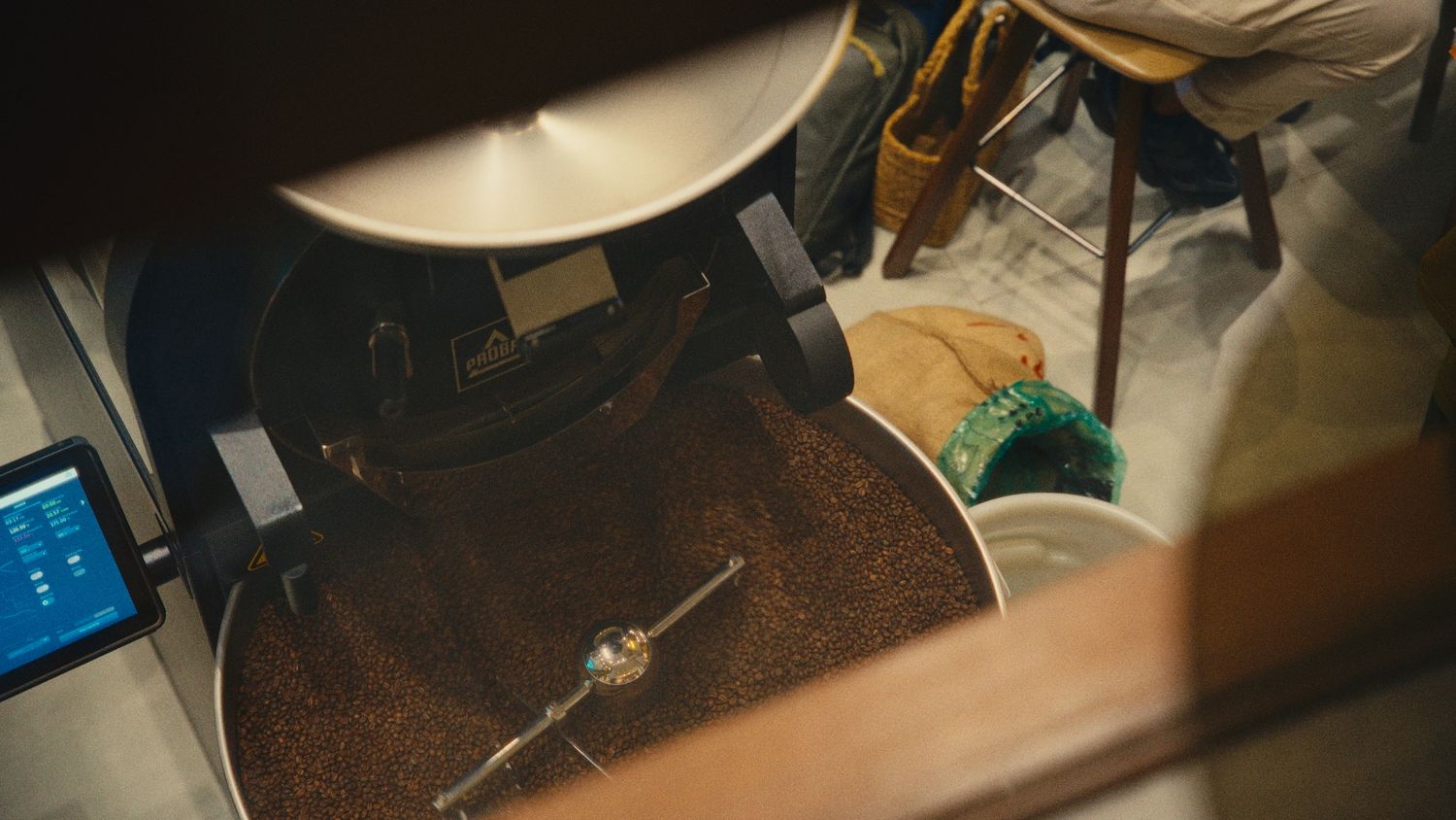 Close-up of coffee beans roasting in a commercial coffee roaster machine in a specialty coffee shop.