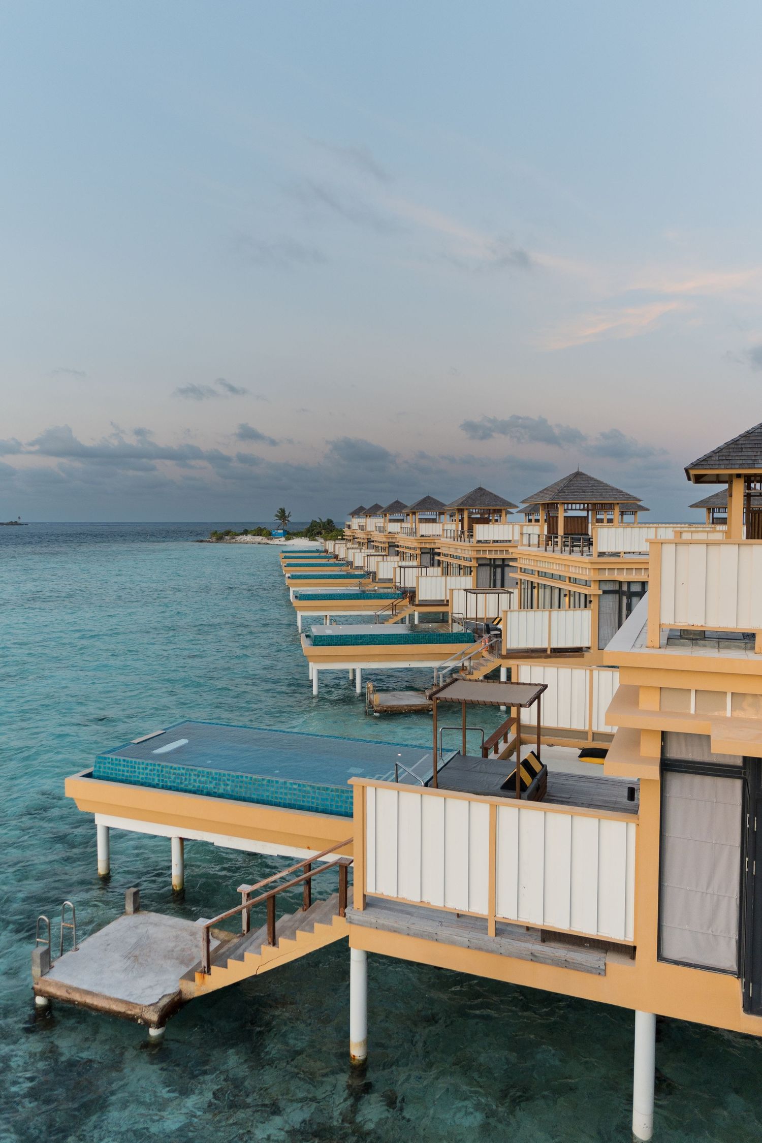 Modern overwater villas with white exteriors extending into pristine turquoise waters.