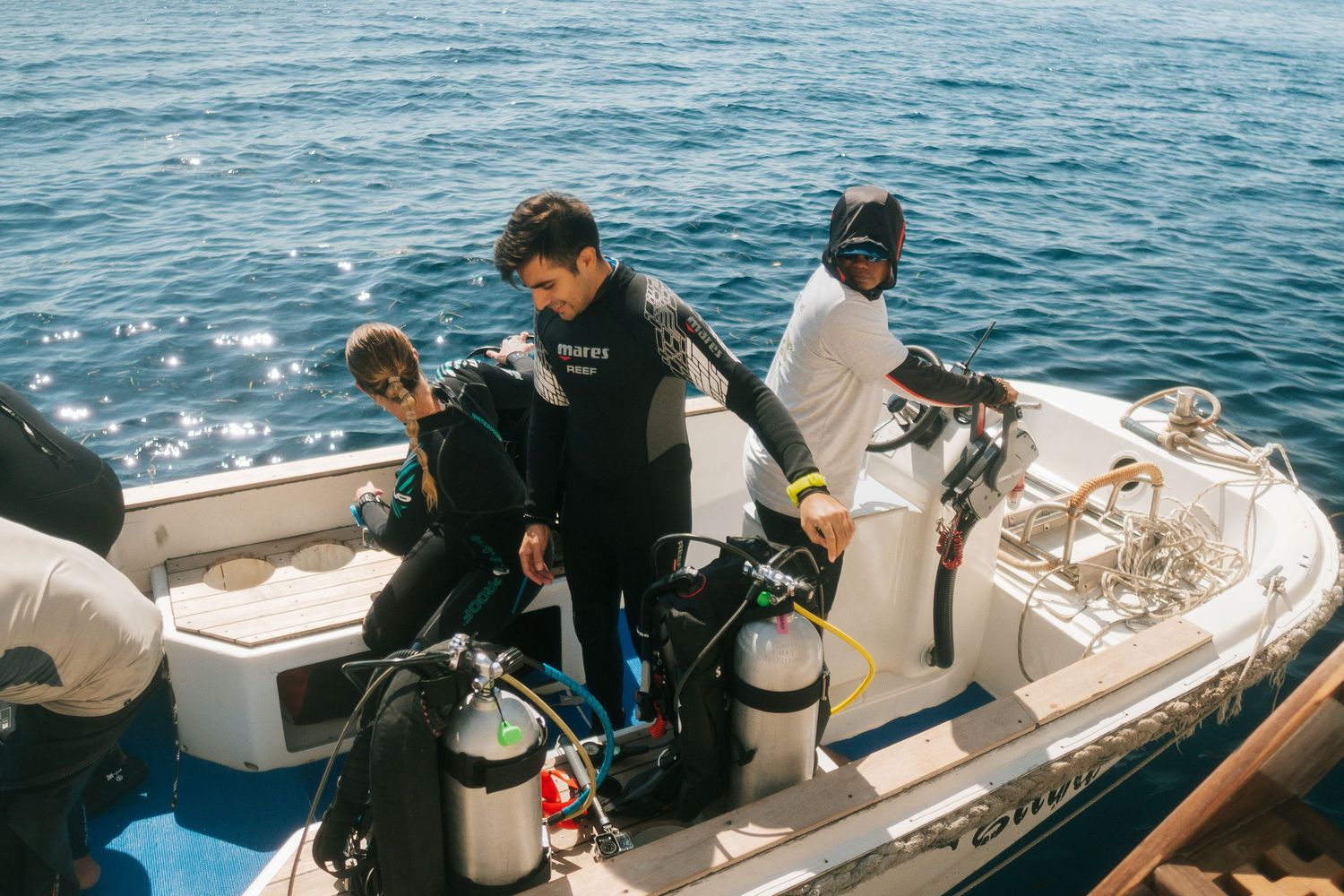 Scuba divers preparing equipment on boat deck for ocean dive expedition.