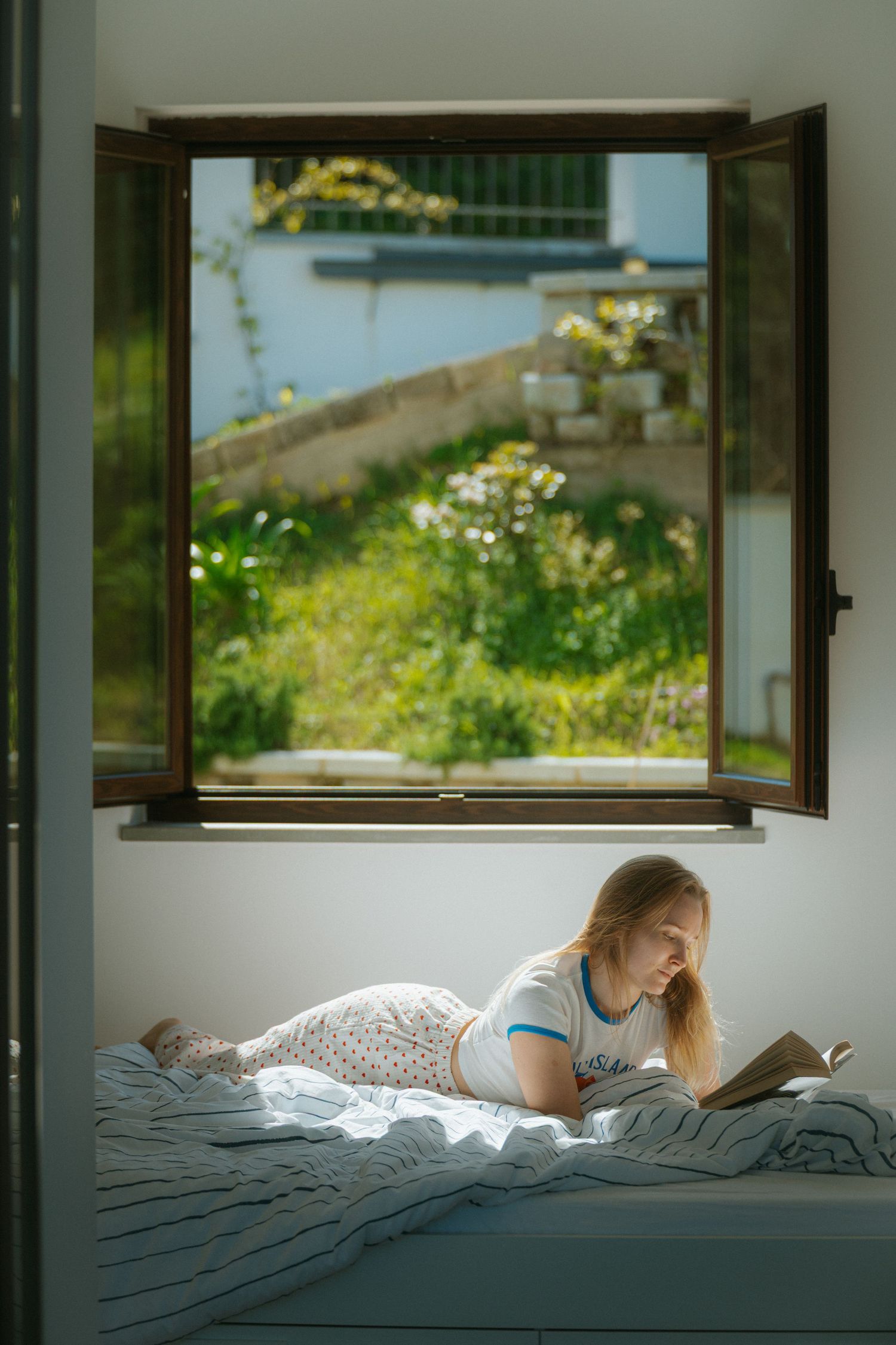 Tranquil reading scene by window with garden views and natural daylight.