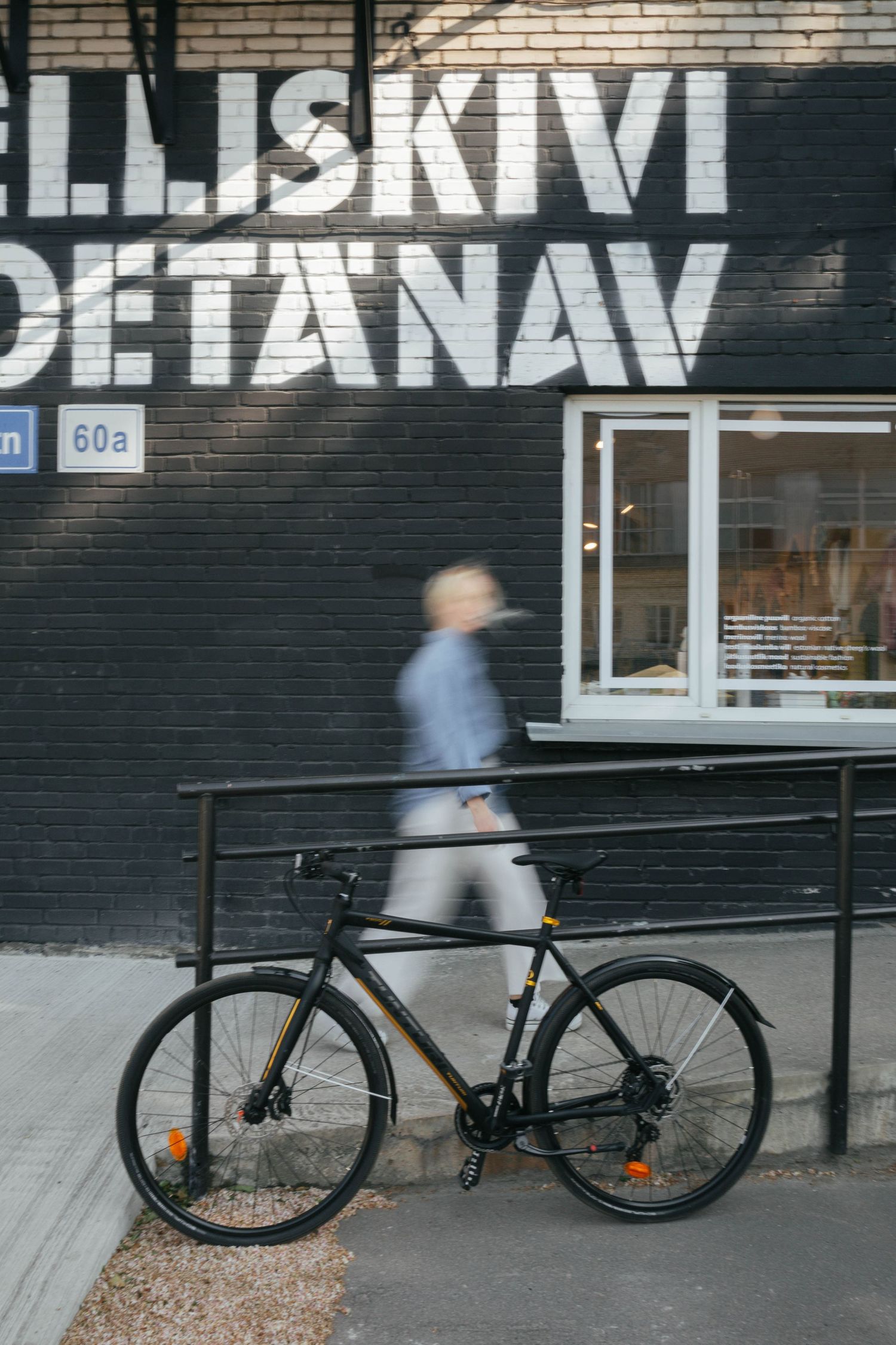 Black racing bicycle parked against dark wall with white text graffiti.