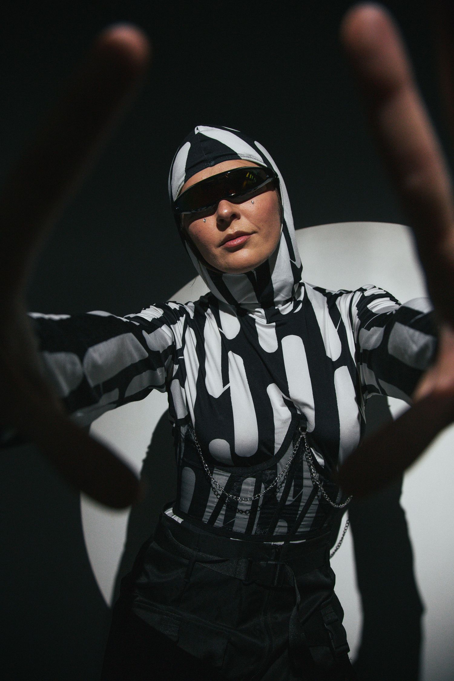 Dramatic black and white striped outfit photographed in dark moody lighting.