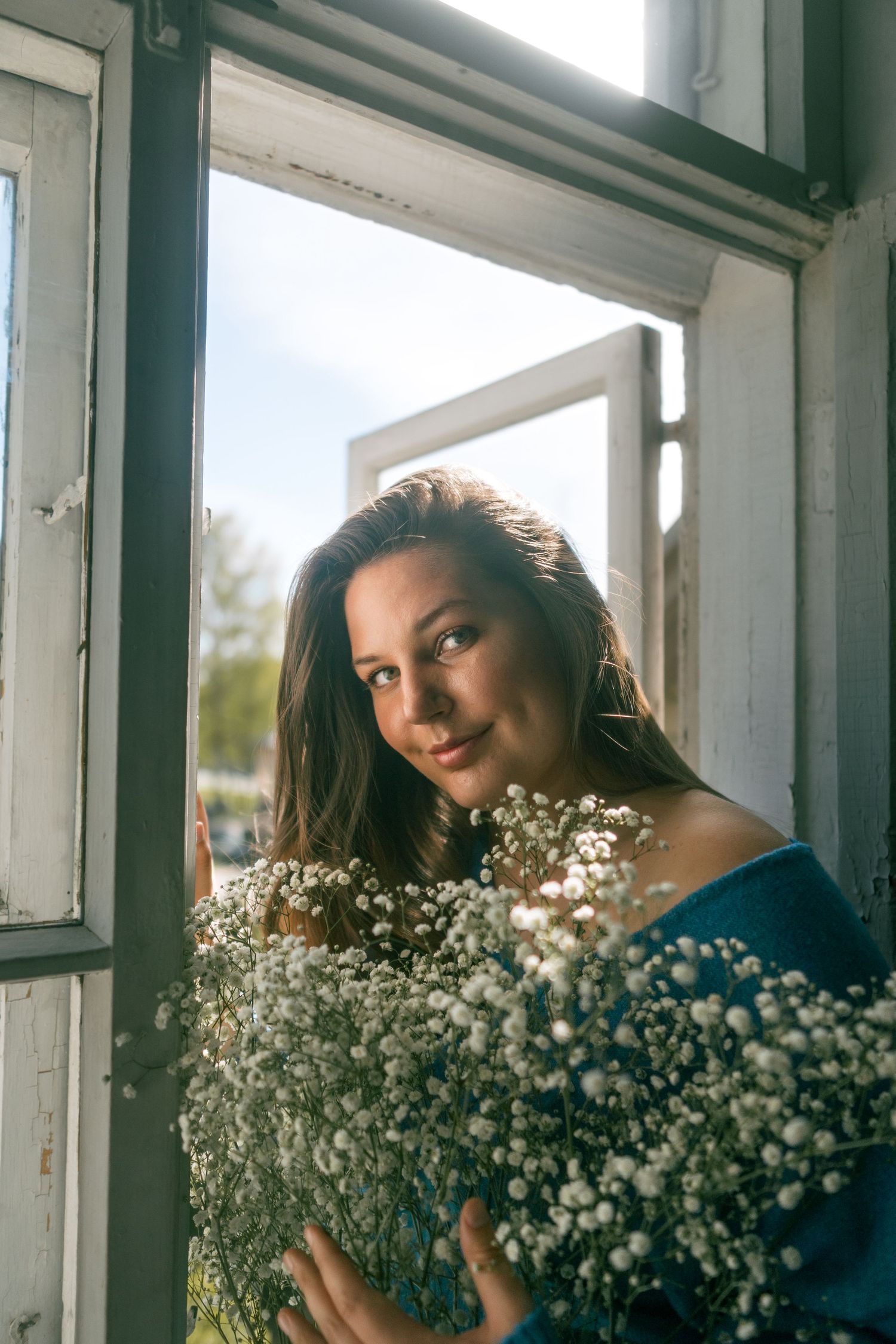 Artistic portrait with baby's breath flowers framing subject near window.