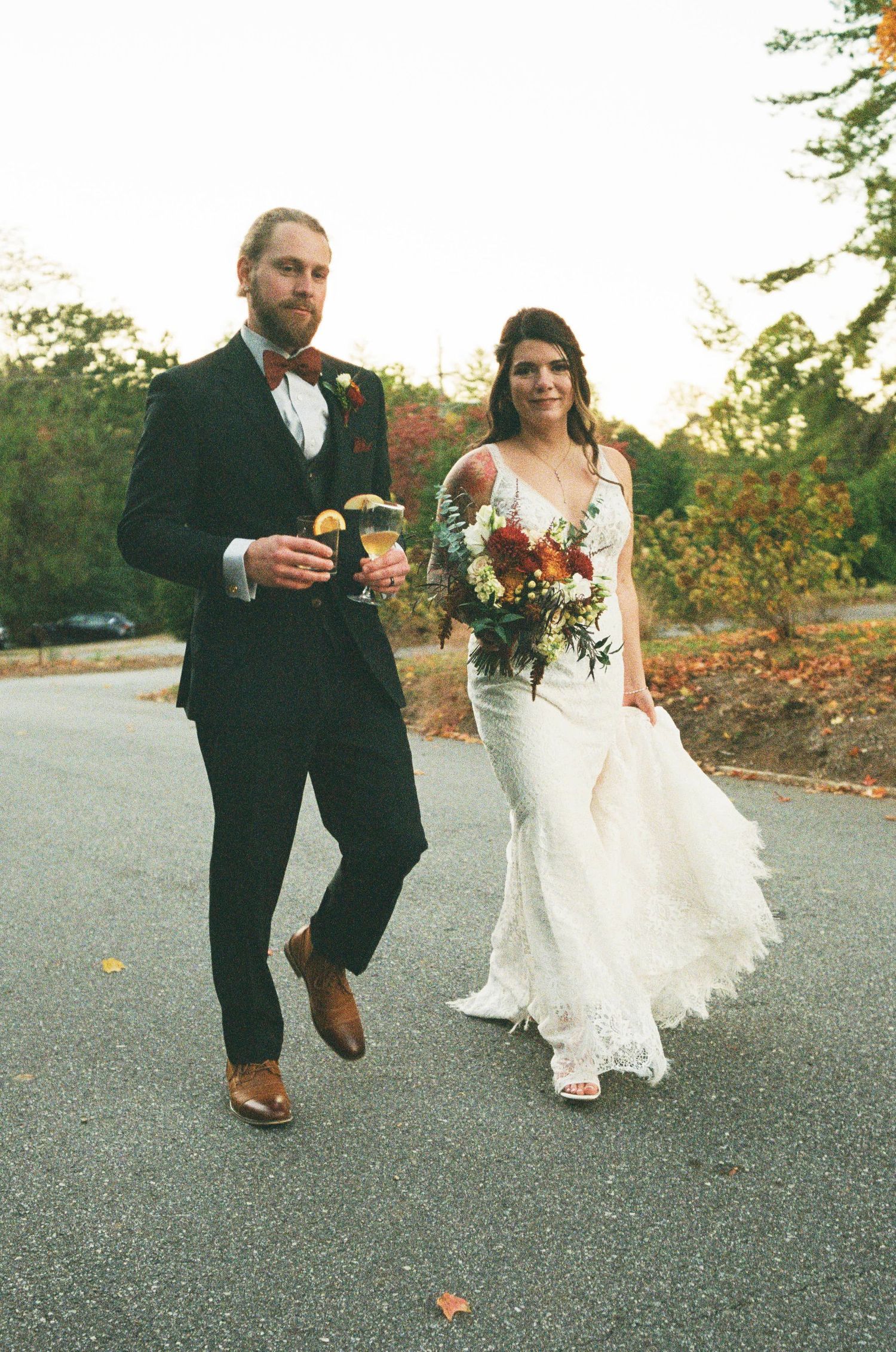 A wedding couple walking together outdoors with the bride carrying a colorful bouquet.