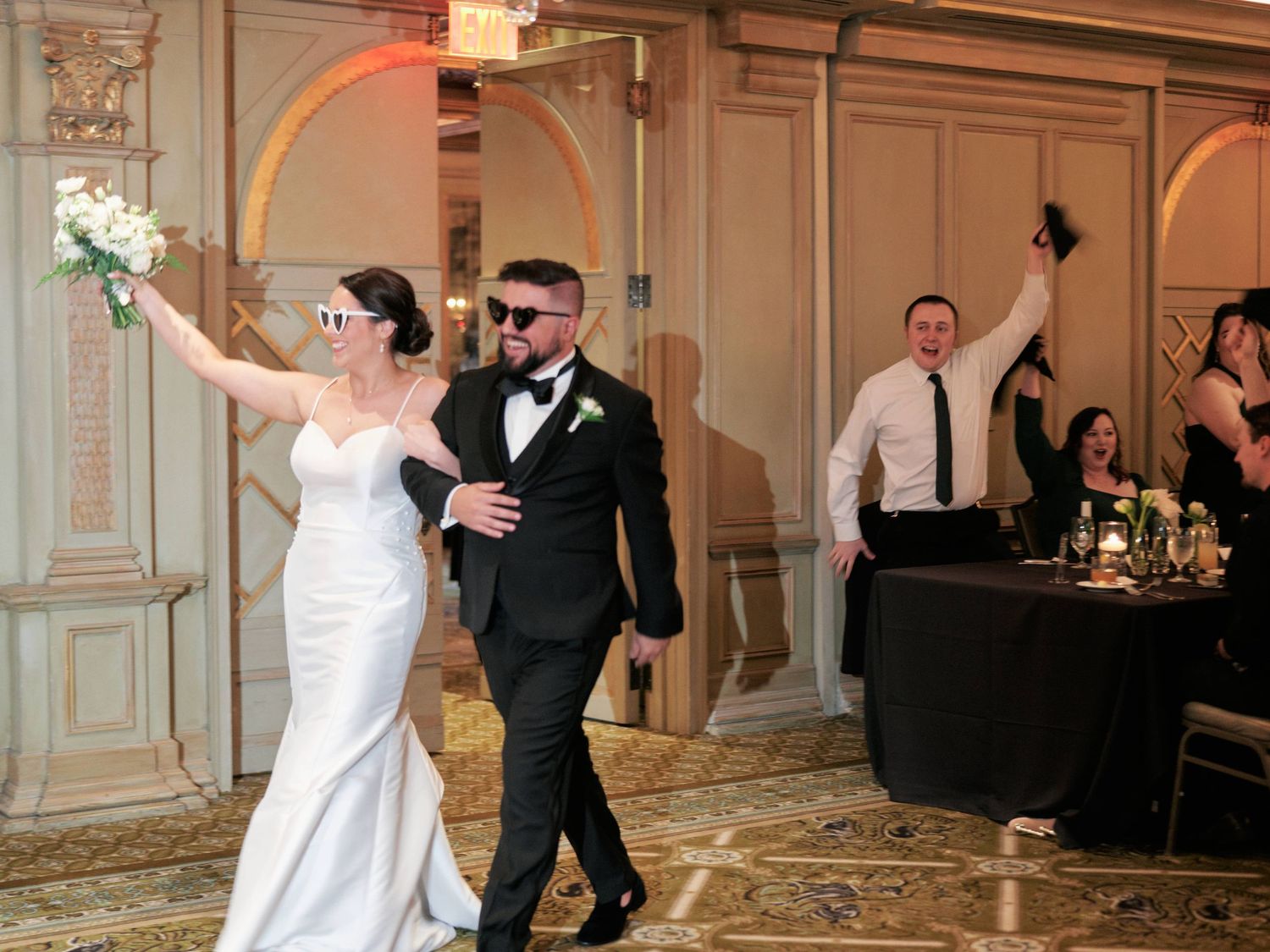 Elegant wedding reception entrance in a grand ballroom with ornate decor and celebrating guests.