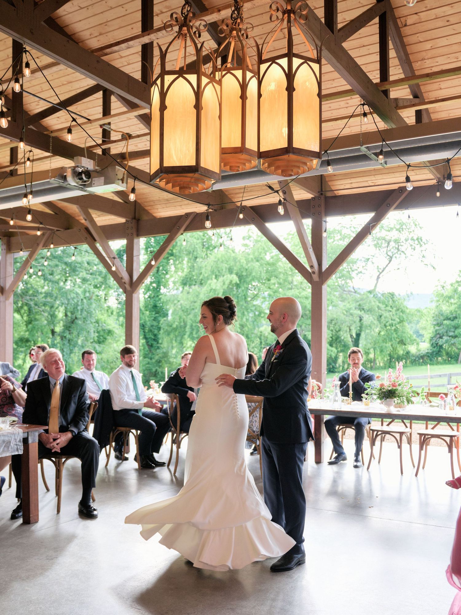 Couple shares their first dance under gothic-inspired lanterns in rustic wooden pavilion.