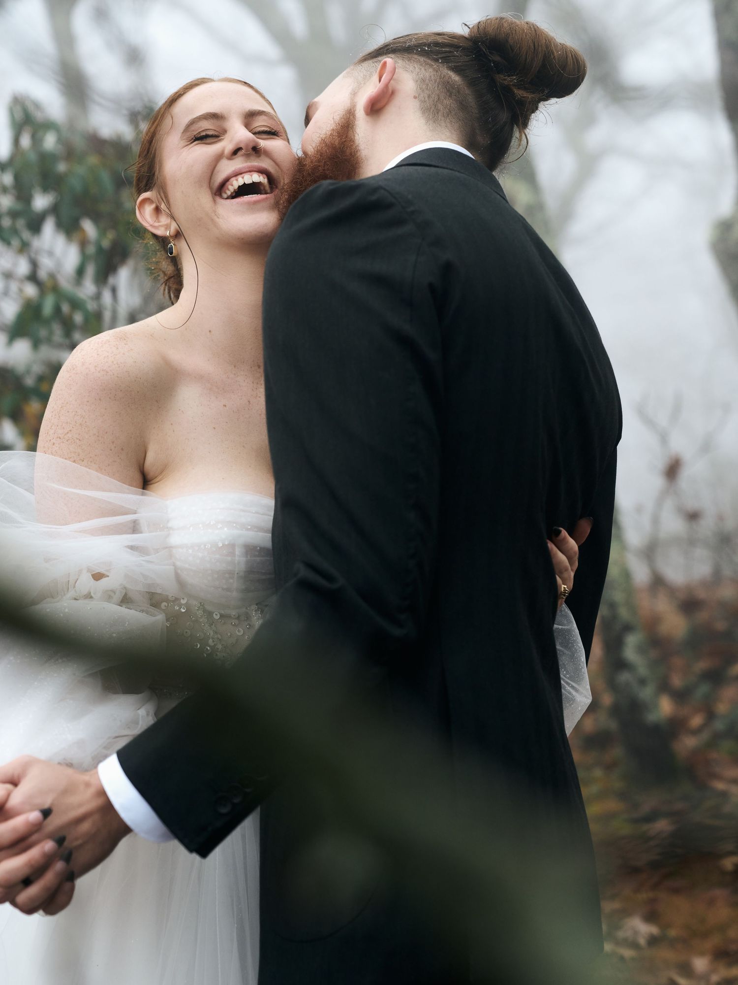 A joyful moment captured between newlyweds in a misty outdoor setting.