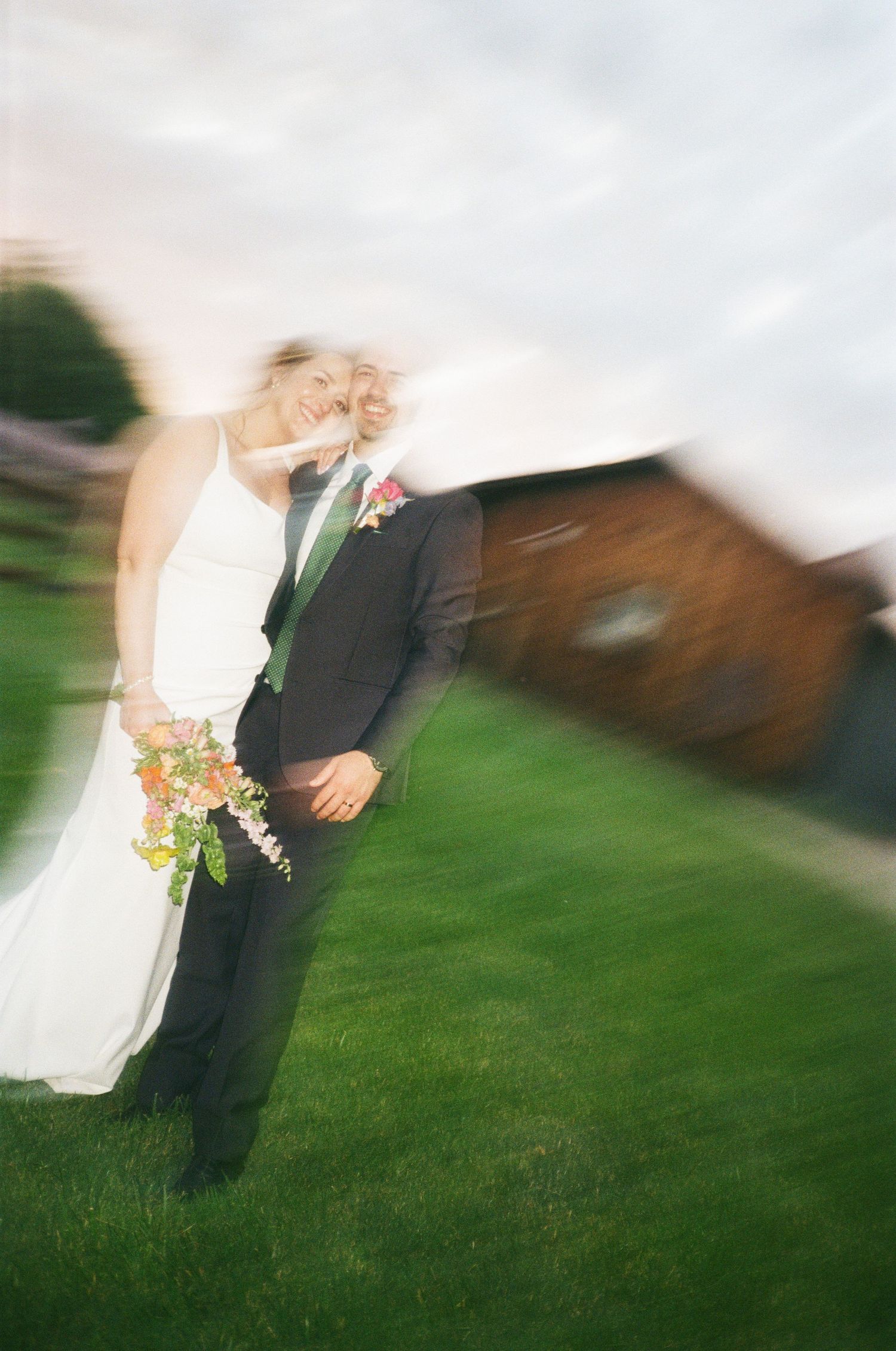 Elegant wedding portrait of couple in formal attire against lush forest backdrop.