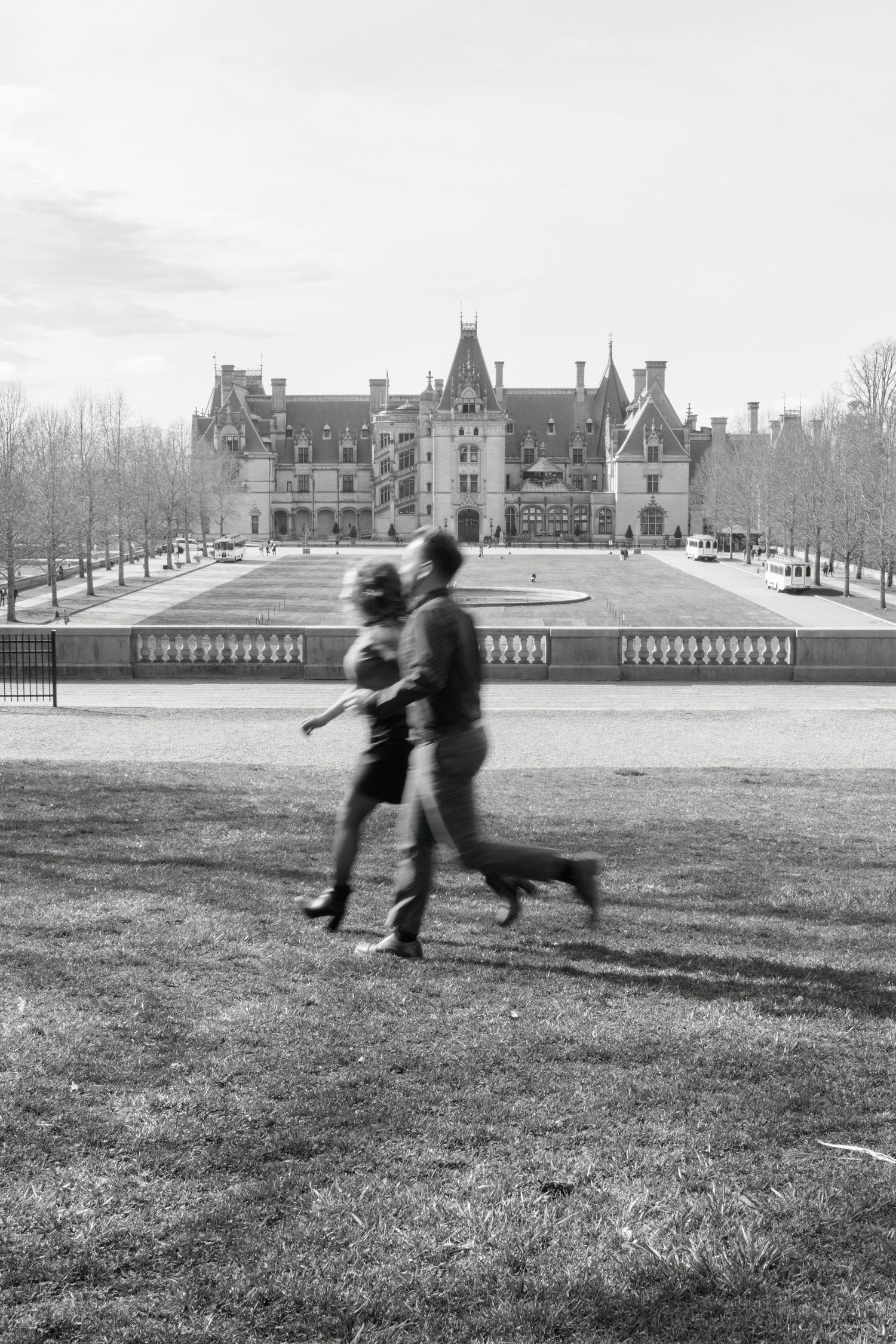 Couple running holding hands in front of the Bitlmore Estate