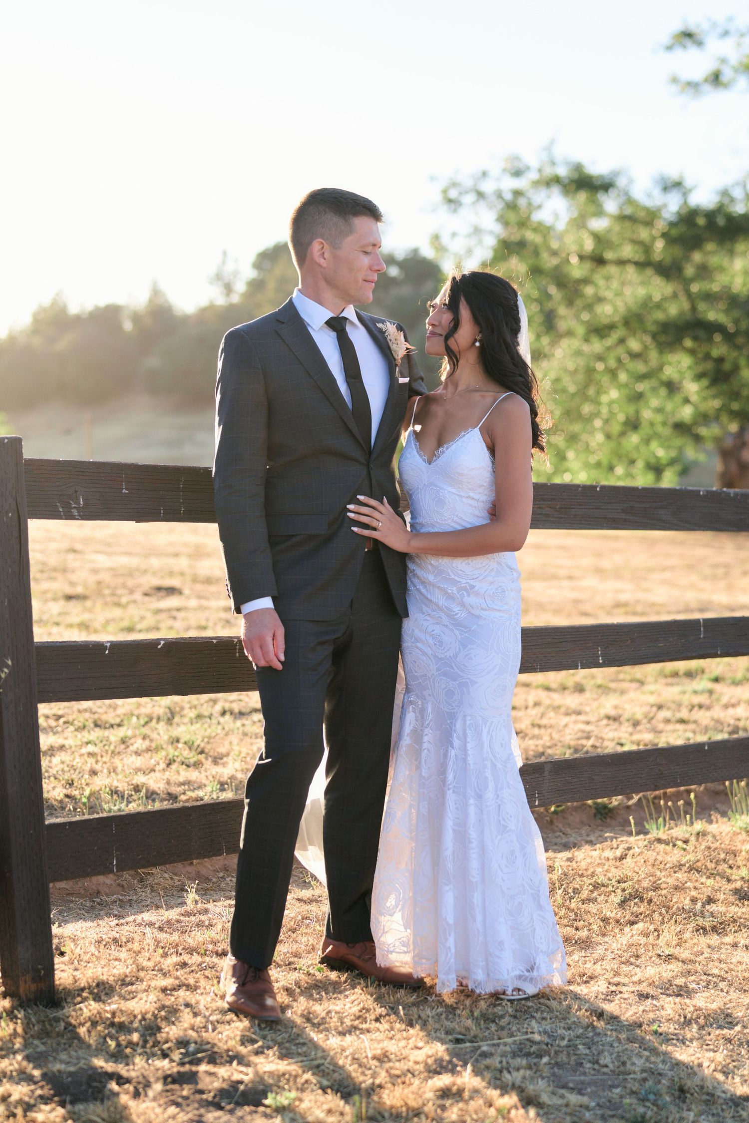 A romantic sunset portrait by a rustic wooden fence in an outdoor setting.