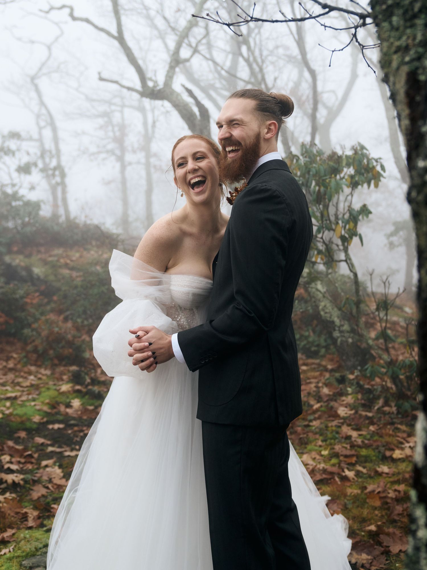 Joyful wedding portrait outdoors on misty autumn day.