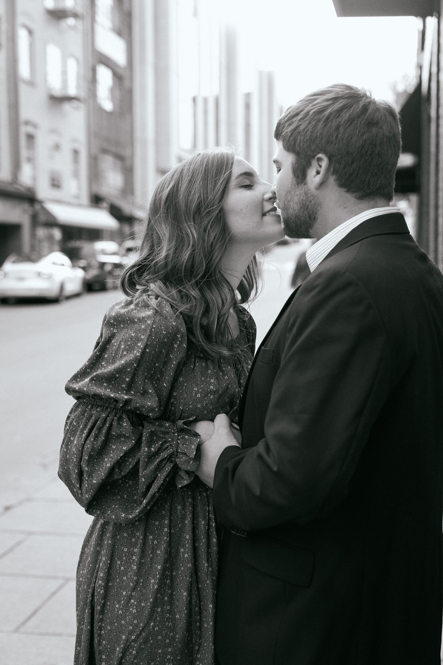 A romantic black and white photo of a couple sharing an intimate moment on a city street.