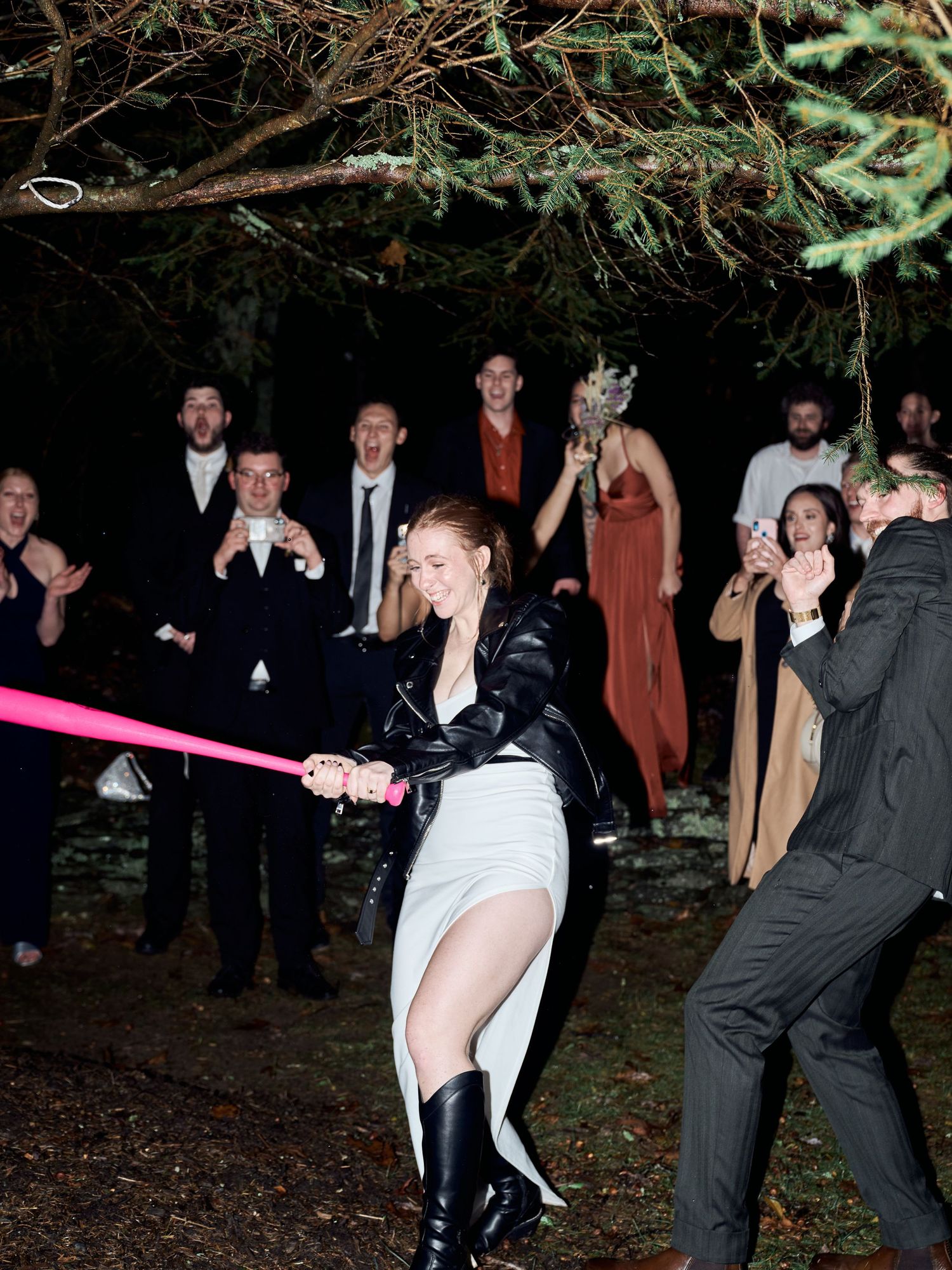 Wedding guest playing limbo game at nighttime outdoor reception party.