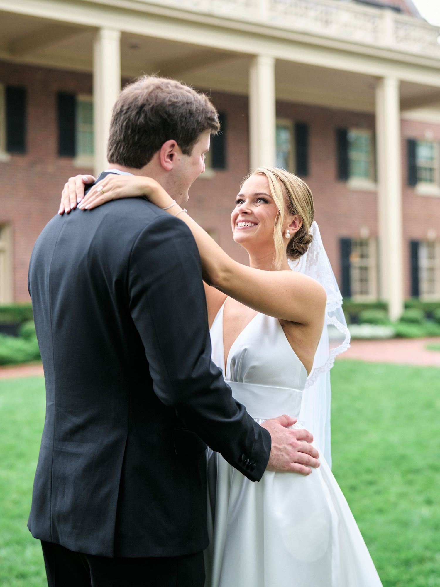 Couple shares an intimate moment during their wedding photos in front of a colonial style mansion.