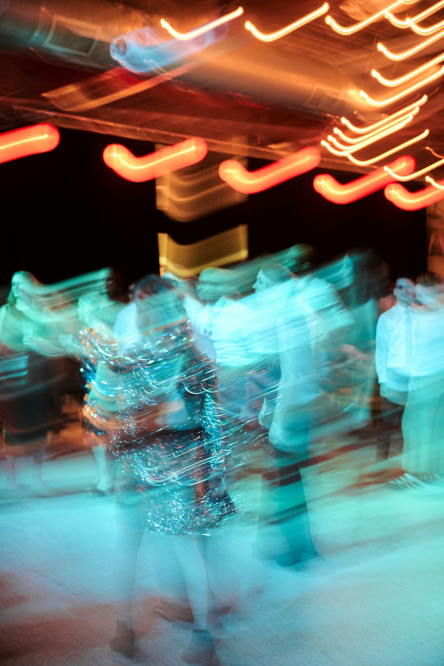 Abstract motion blur of dancers under blue and orange lights creates a dreamy atmosphere.