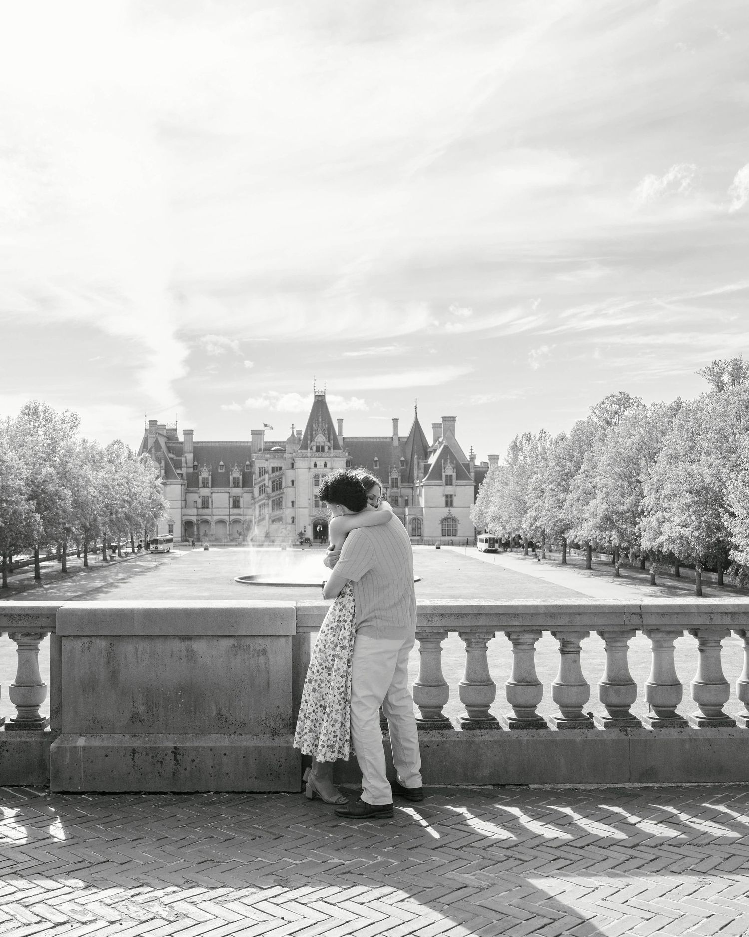 Couple embracing on a terrace overlooking the grand Biltmore Estate in a black and white photo.