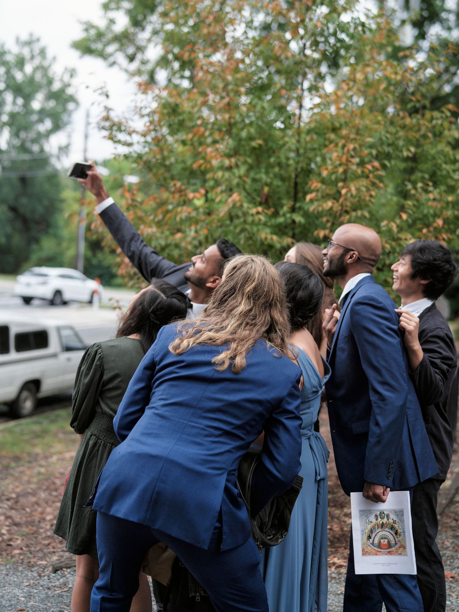 Wedding guests taking selfies together outside during autumn.