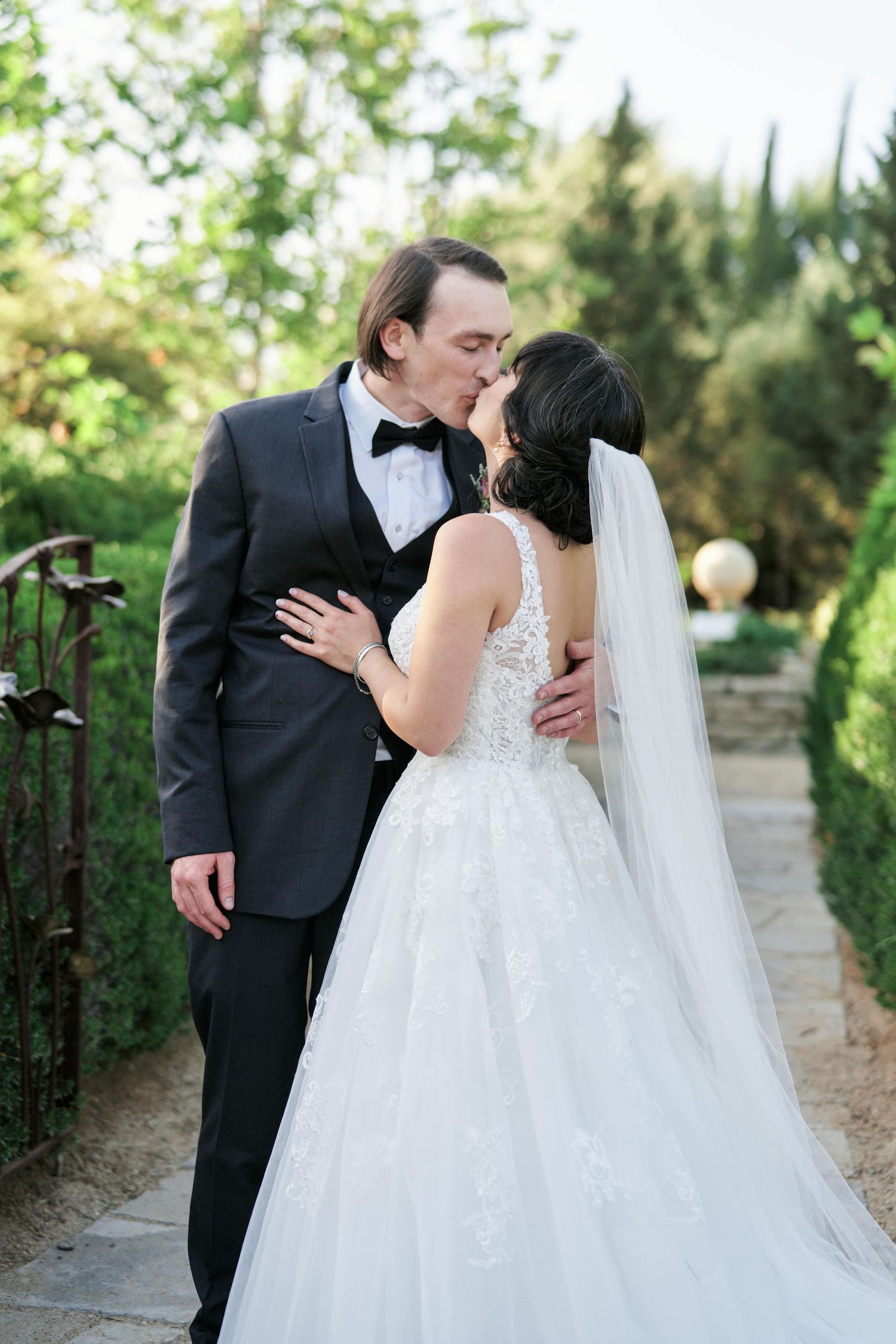 A romantic moment between newlyweds on a stone path in a garden setting.