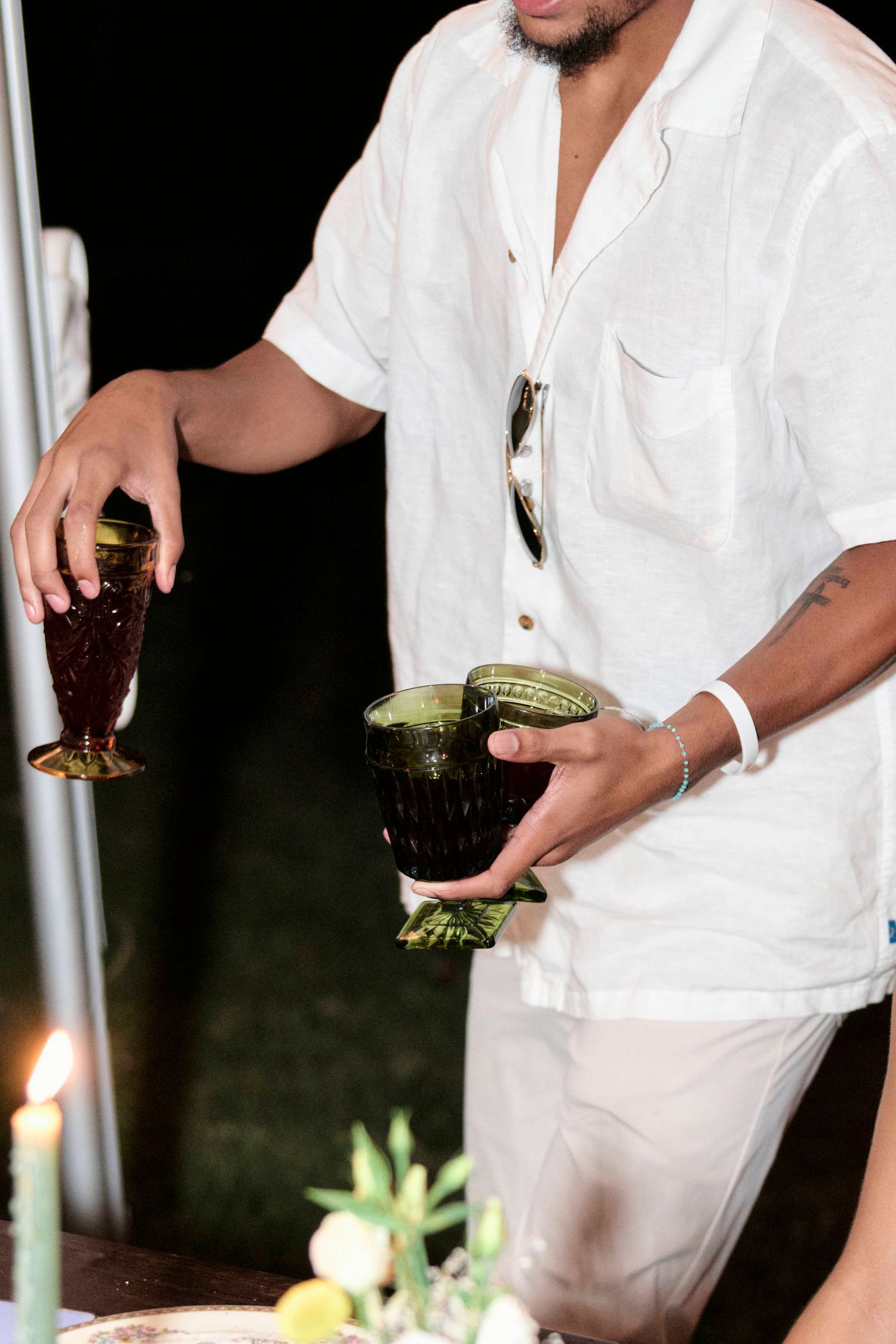 Person in white attire preparing cocktails at an outdoor event.