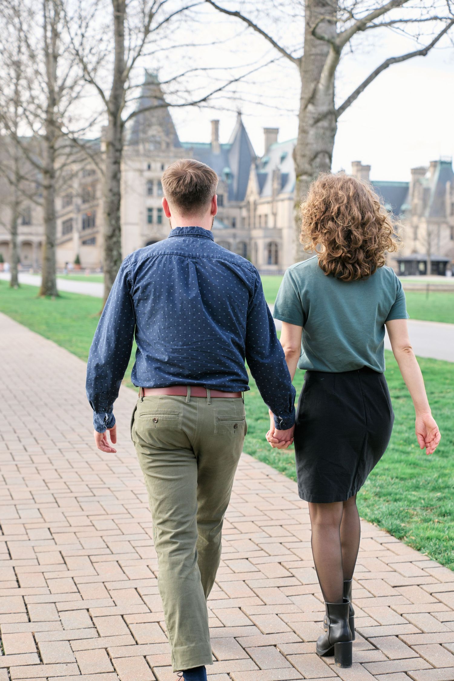 Couple walking in front of the Biltmore House during their engagement photos.