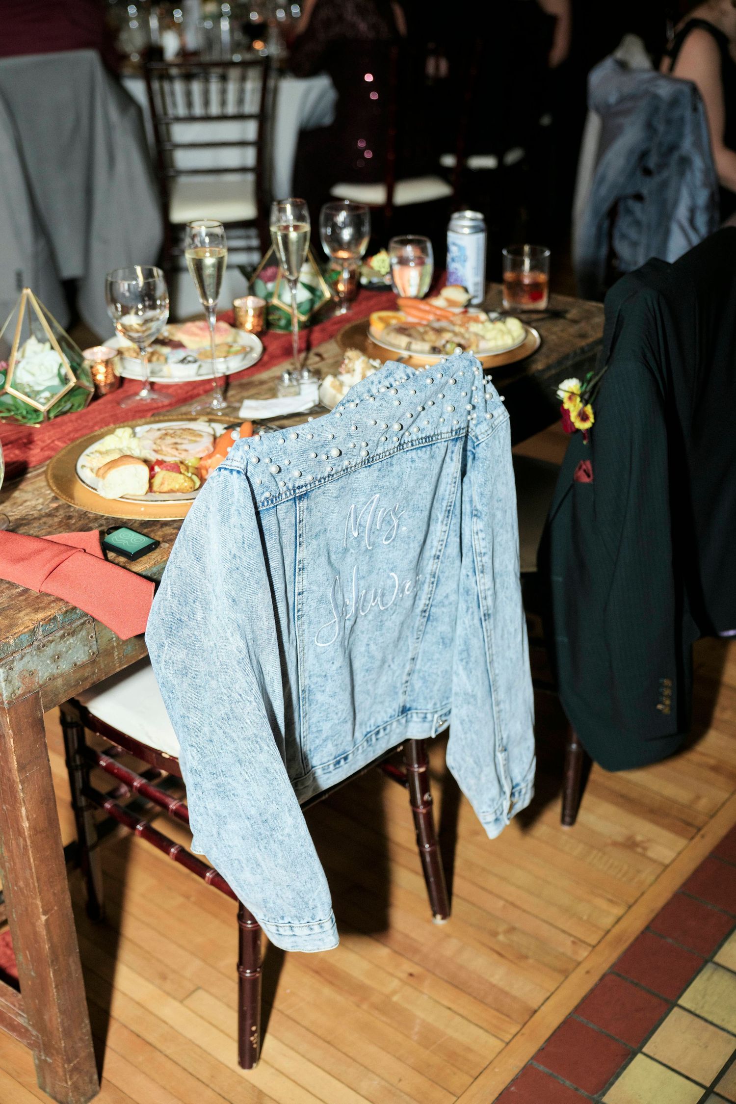Reception table with food platters and denim jacket draped over wooden chair.