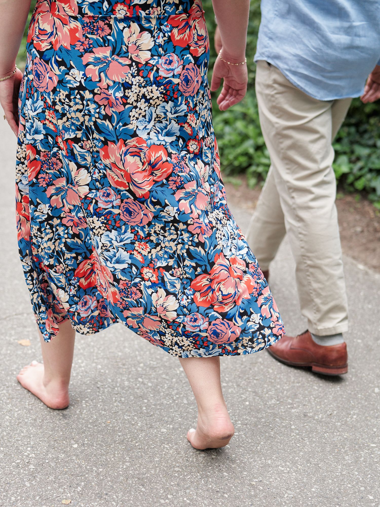 Close-up of floral dress and bare feet walking on path.