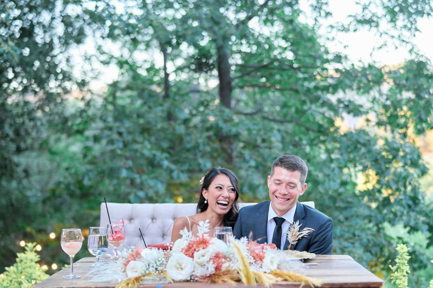 A joyful scene at an outdoor wedding reception with table settings and floral arrangements.