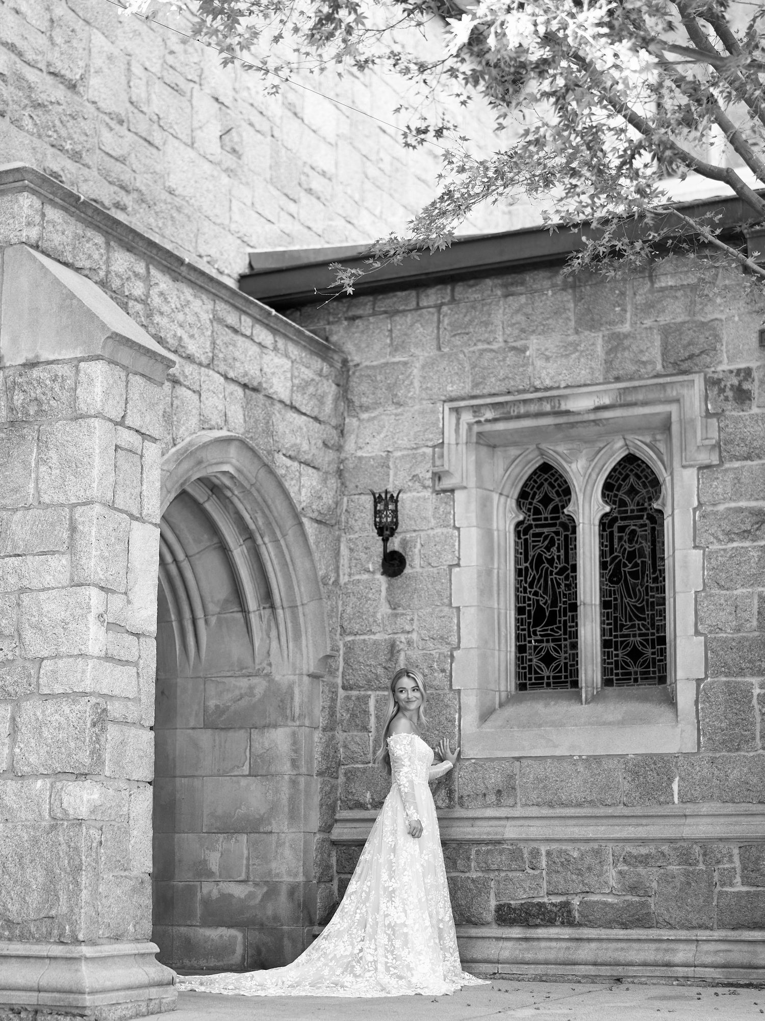 Classic black and white bridal portrait at gothic stone church with arched doorway.