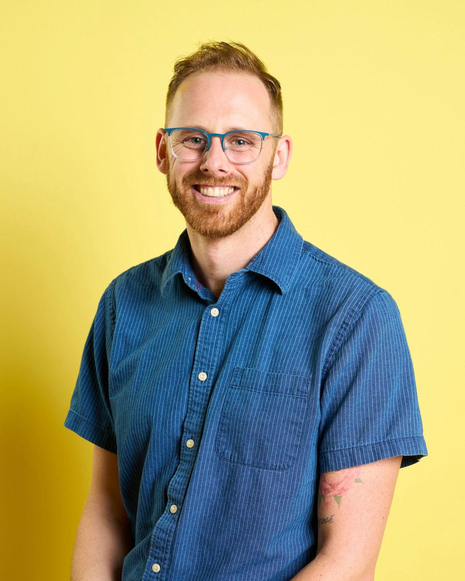 Professional headshot of a men sitting in front of a yellow backdrop.